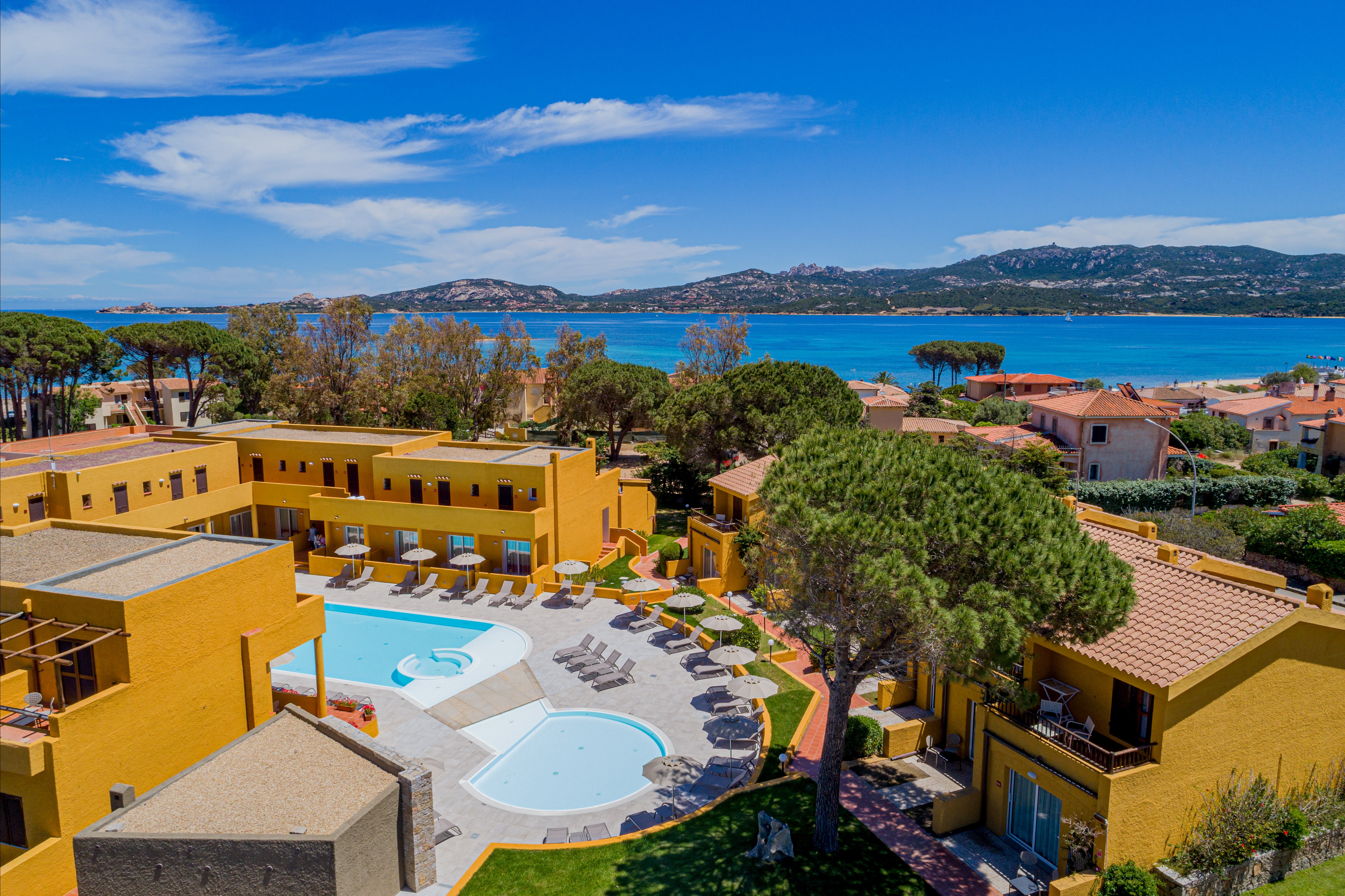 Vasaras kūrorts ar dzeltenām ēkām, baseinu un skaistu skatu uz jūru un kalniem. Ideāla vieta relaksācijai un atpūtai. panoramic view with beach and pools