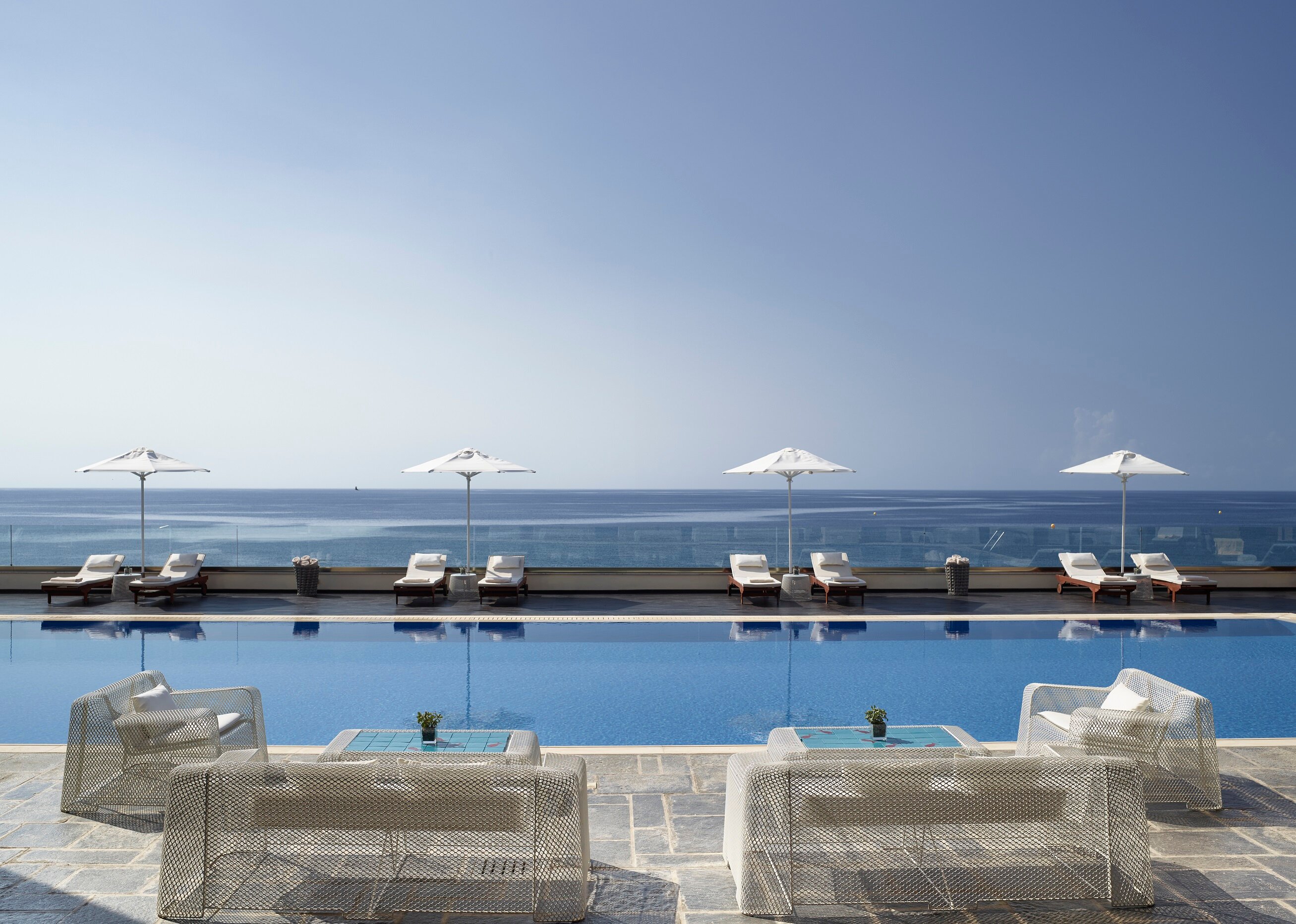 Eleganta peldbaseina zona ar sauļošanās krēsliem un saules sargiem, kas atrodas pie jūras. Ideāla vieta relaksācijai un atpūtai. panoramic view with beach and pools
