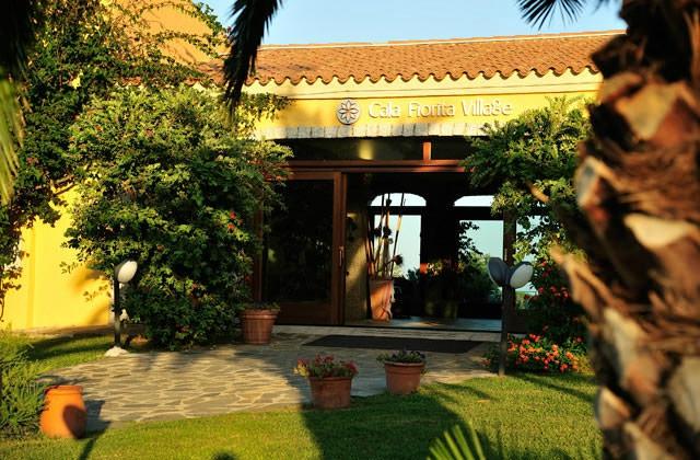 Futura Cala Fiorita ieeja ar zaļiem augiem un dārza ainavu.