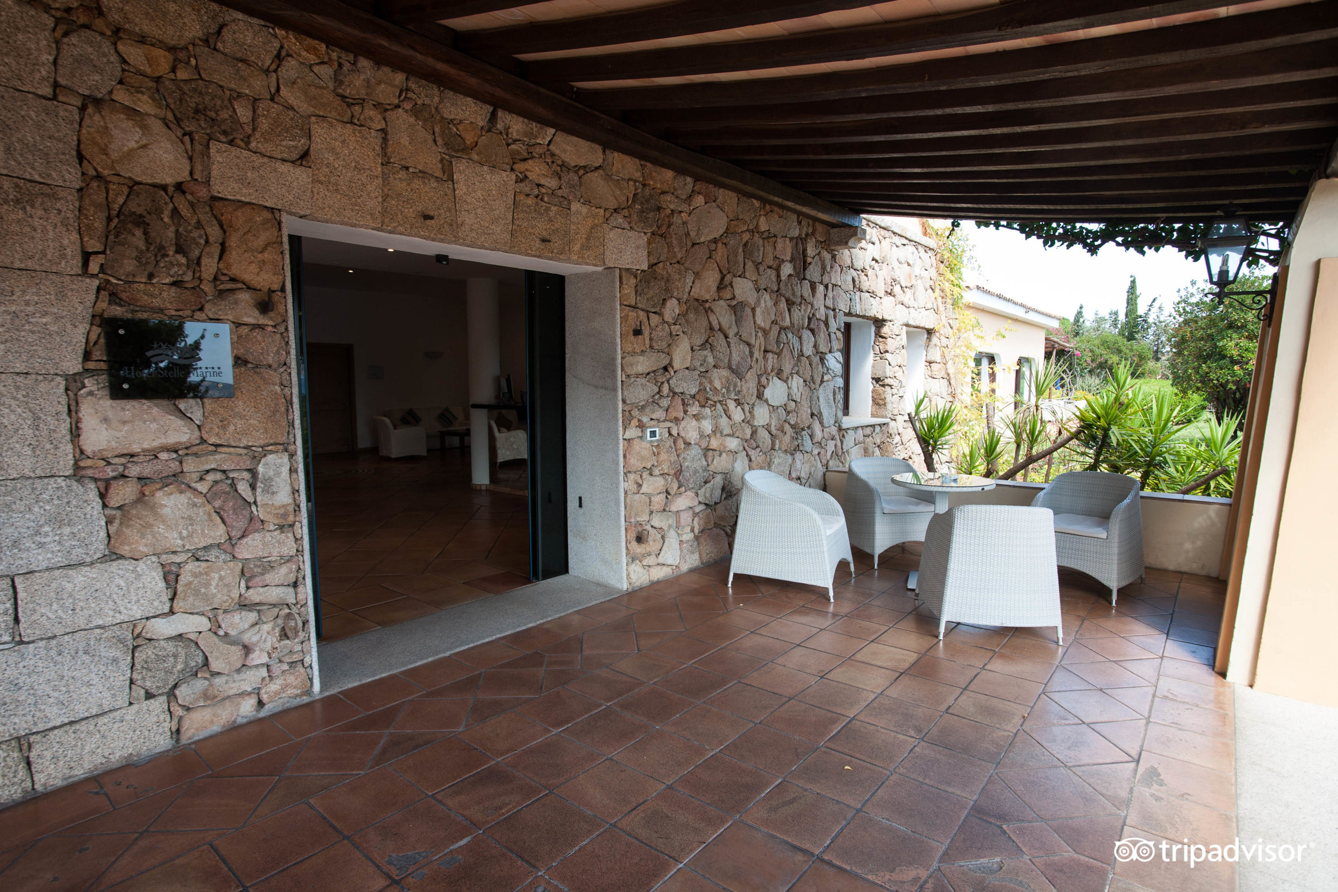 Āra terase viesnīcā Hotel Stelle Marine ar akmens sienu un baltām mēbelēm.