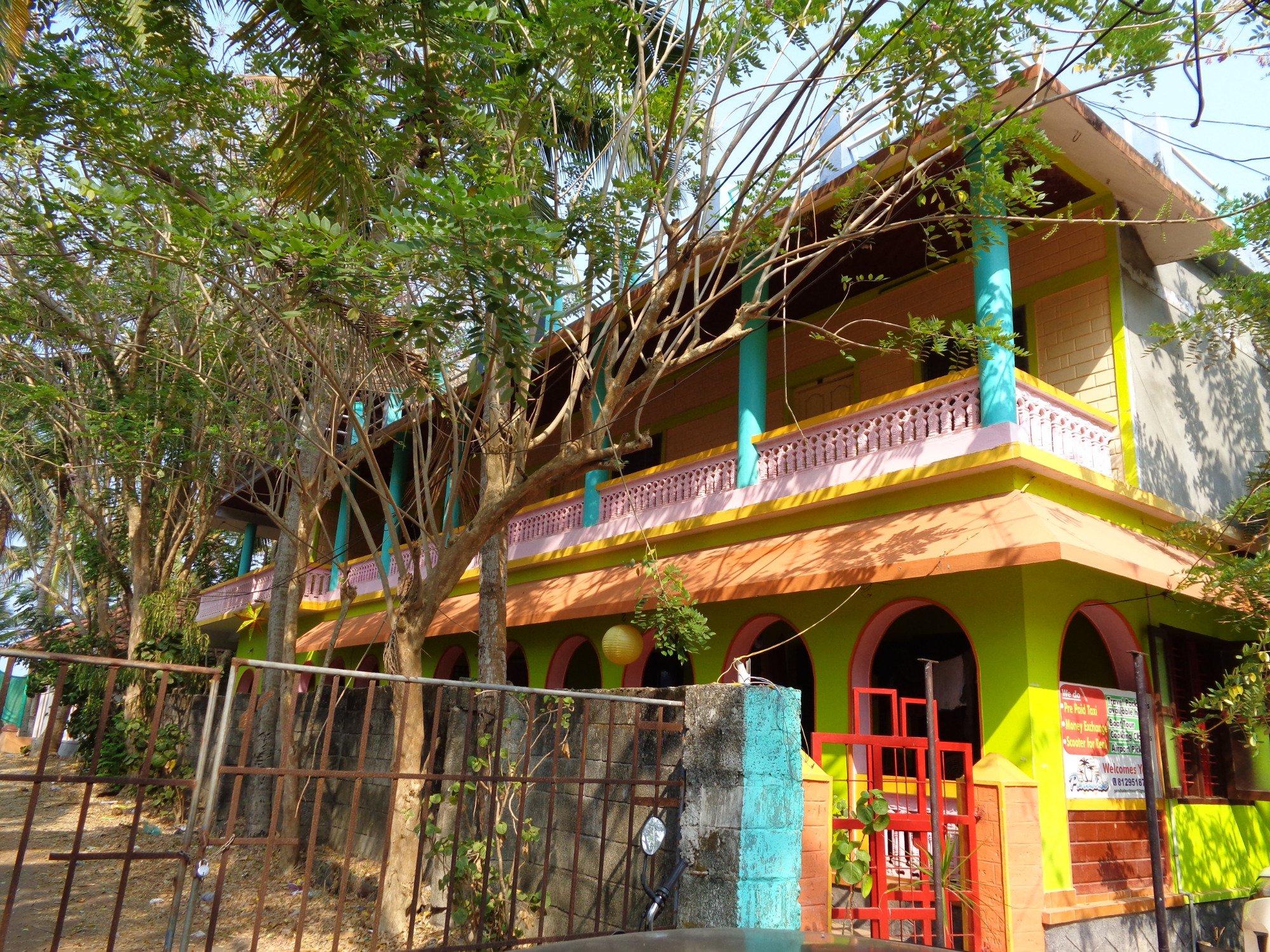 Krāsaina ēka ar balkonu un kokiem priekšplānā Paradise Beach Resort.