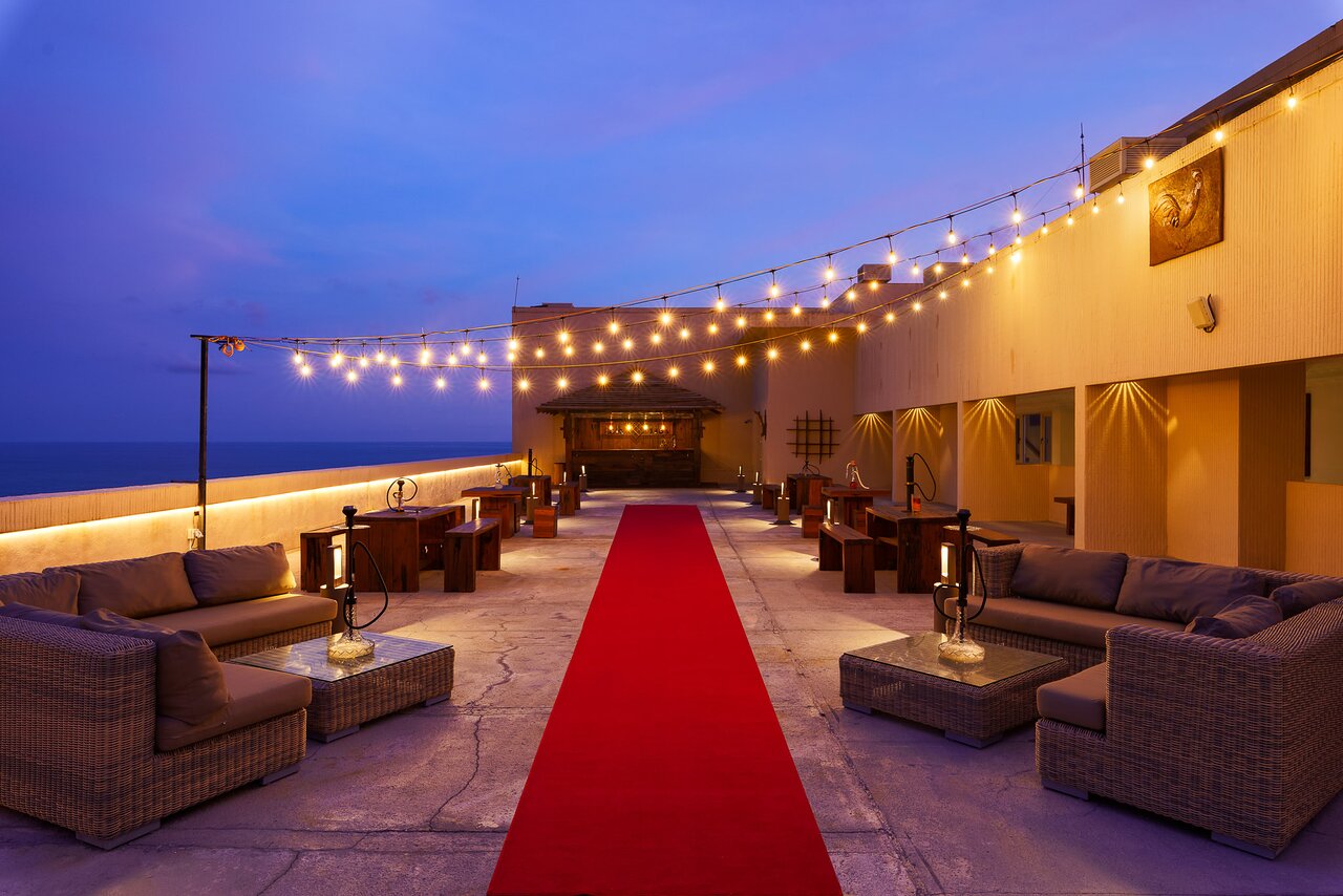 Araliya Beach Resort & Spa terase ar skatu uz jūru un vakara apgaismojumu.