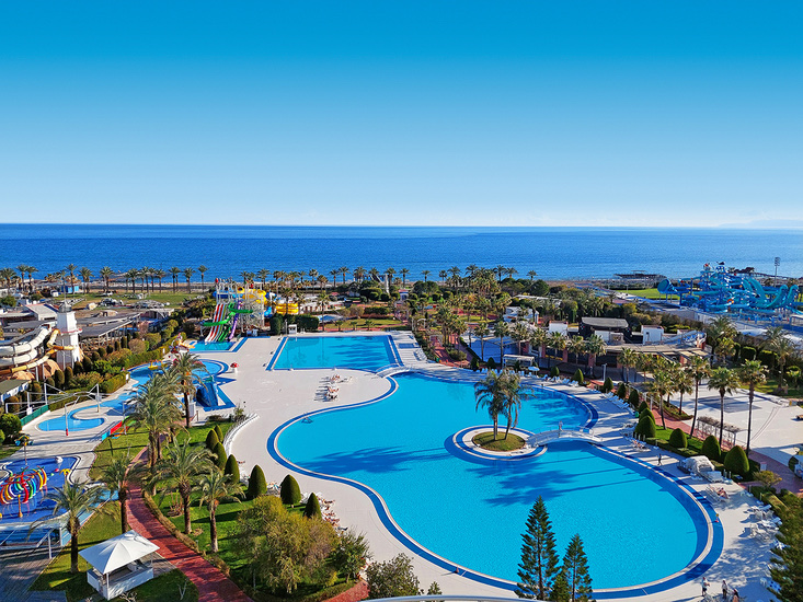 Miracle Resort Hotel plašā teritorija Antalijā ar lielu āra baseinu, akvaparku un skatu uz Vidusjūru saulainā dienā
