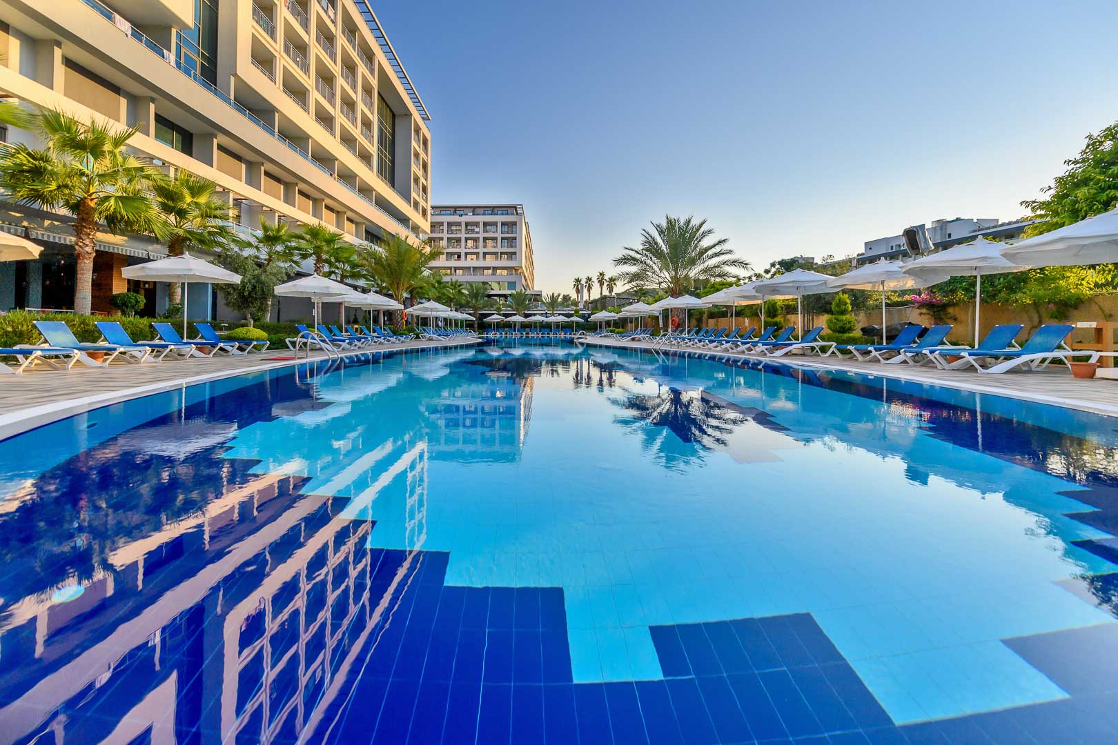 Plašs Numa Bay Exclusive Hotel āra baseins ar ziliem sauļošanās krēsliem un saulessargiem Alānijā, Turcijā