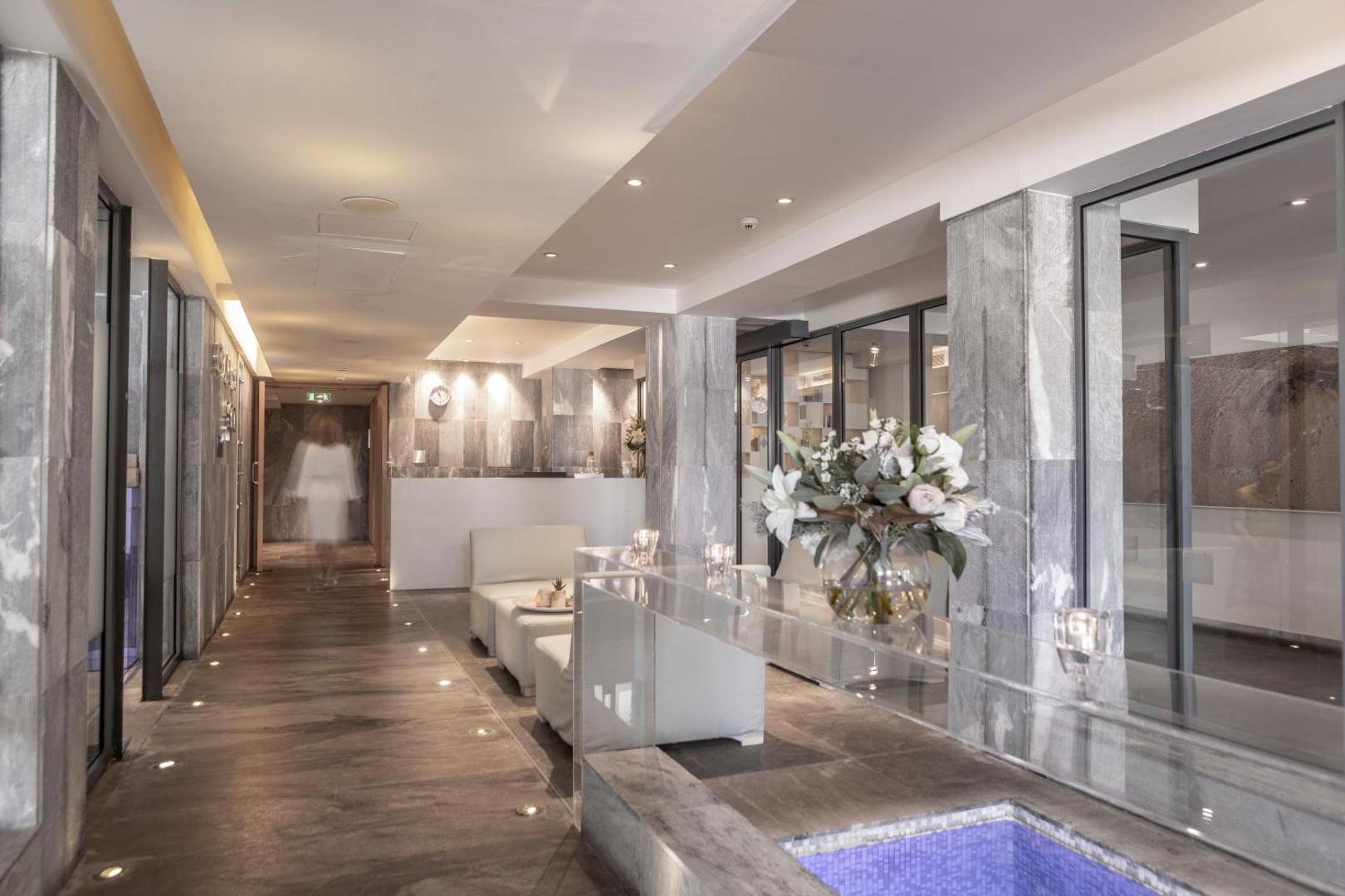 Capo Bay Beach Hotel spa centra recepcija un gaitenis ar modernu dizainu, pelēka akmens apdari un ziedu kompozīciju