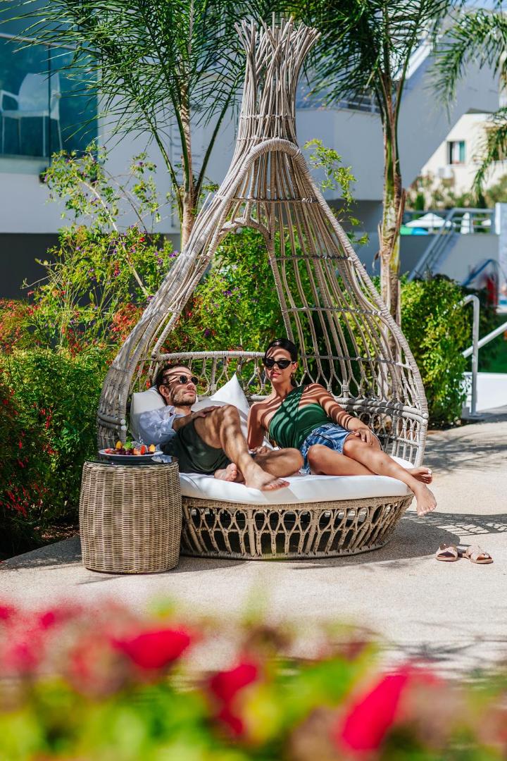 Atpūtas zona Sofianna Resort & Spa dārzā ar stilīgu pīto zvilni un palmu ēnām Pafasā, Kiprā