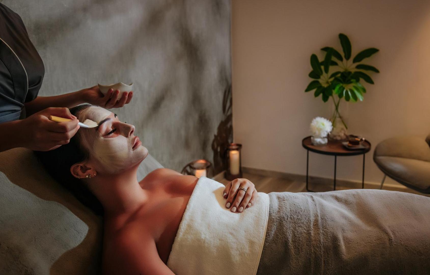 Sofianna Resort & Spa sejas procedūra spa centrā Pafasā, Kiprā — sieviete relaksējas, kamēr speciālists uzklāj masku mierīgā gaisotnē