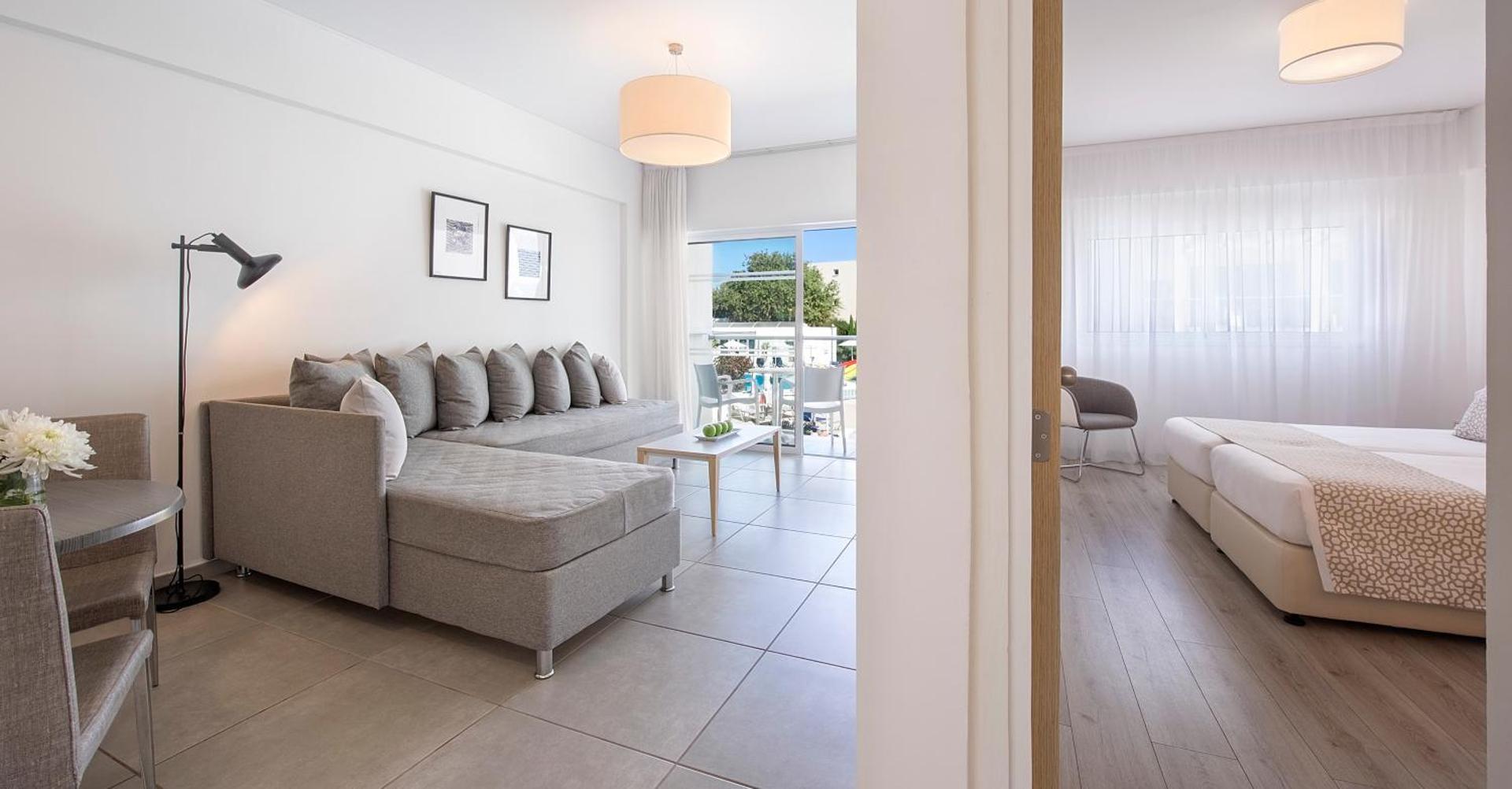 Sofianna Resort & Spa plašs ģimenes numurs ar atsevišķu dzīvojamo zonu, dīvānu un balkonu, no kura paveras skats uz kūrortu