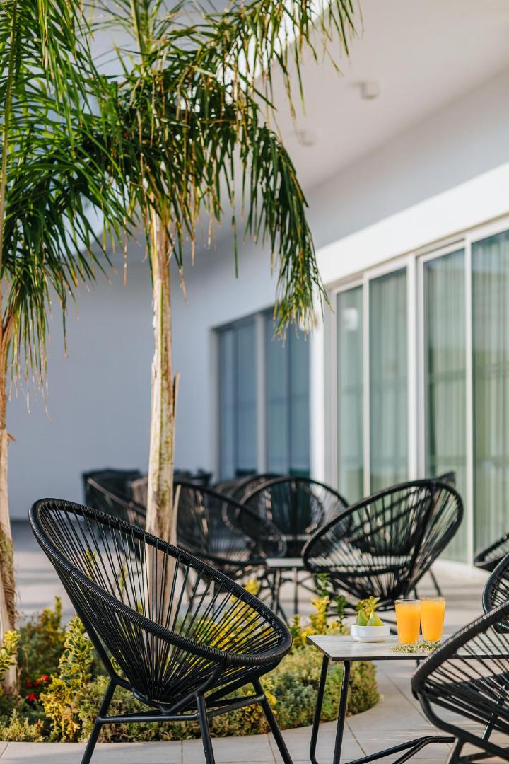 Sofianna Resort & Spa āra terase ar dizaina krēsliem, palmām un svaigi spiestu sulu Pafasā, Kiprā