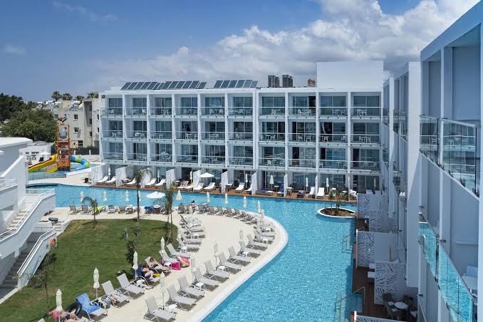 Sofianna Resort & Spa āra baseinu zona Pafā, Kiprā — skats uz viesnīcas korpusiem, sauļošanās krēsliem un bērnu ūdens slidkalniņiem