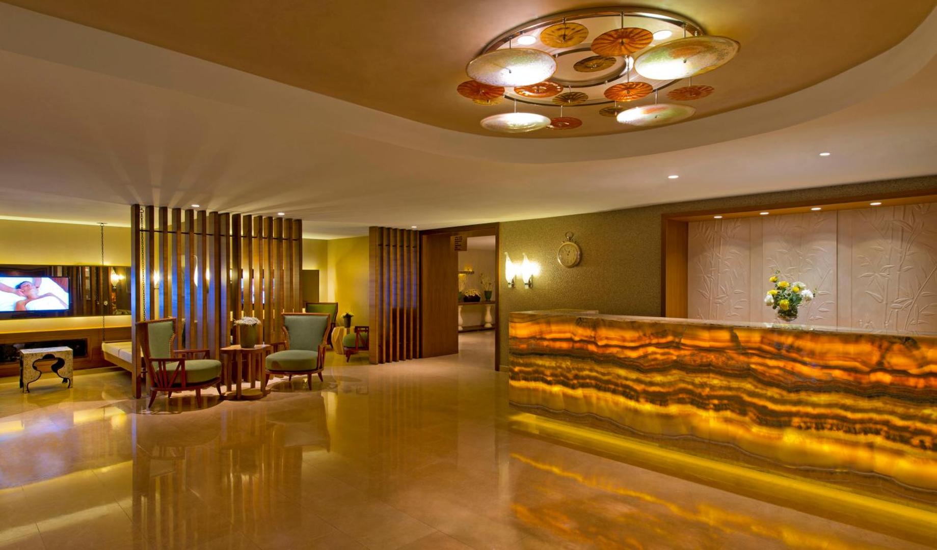 Titanic Deluxe Lara spa zonas recepcija ar izgaismotu oniksa leti, modernām lustrām un ērtu atpūtas zonu viesiem