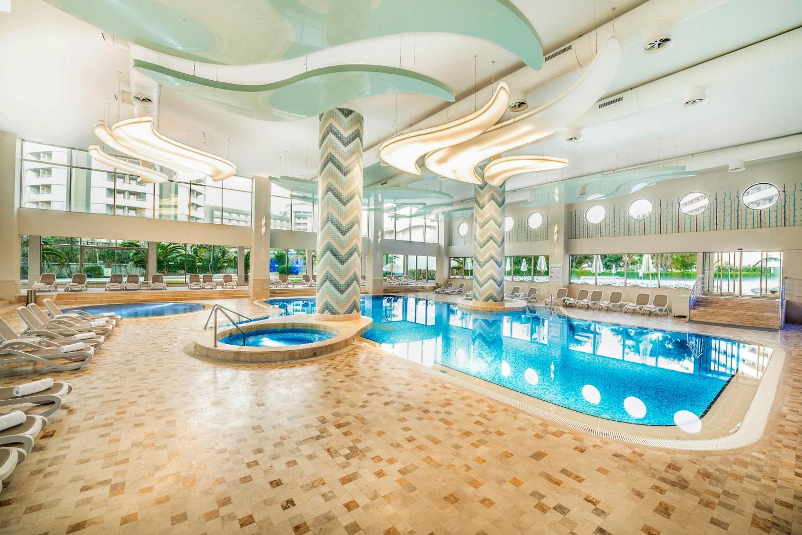 Titanic Deluxe Lara iekštelpu spa centrs ar apsildāmu baseinu, džakuzi zonu un atpūtas krēsliem modernā dizainā