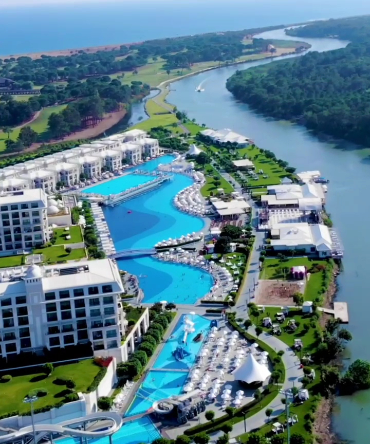 Aerofoto skats uz Titanic Deluxe Golf Belek baseiniem, upes līkumu un apkārtējo zaļo golfa laukumu zonu Belekā