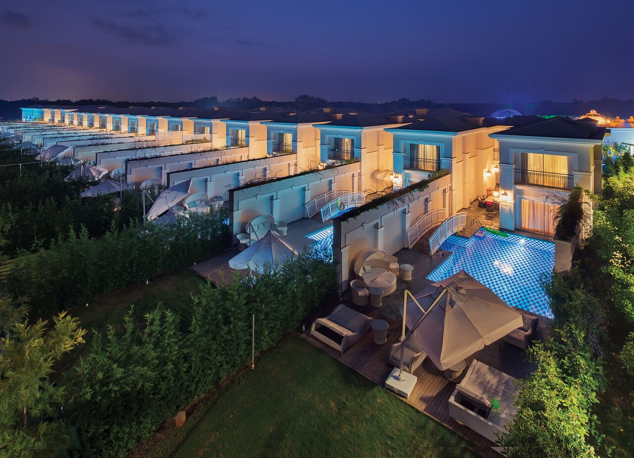 Viesnīcas Titanic Deluxe Golf Belek luksusa villas ar privātiem baseiniem un izgaismotām terasēm vakara noskaņā