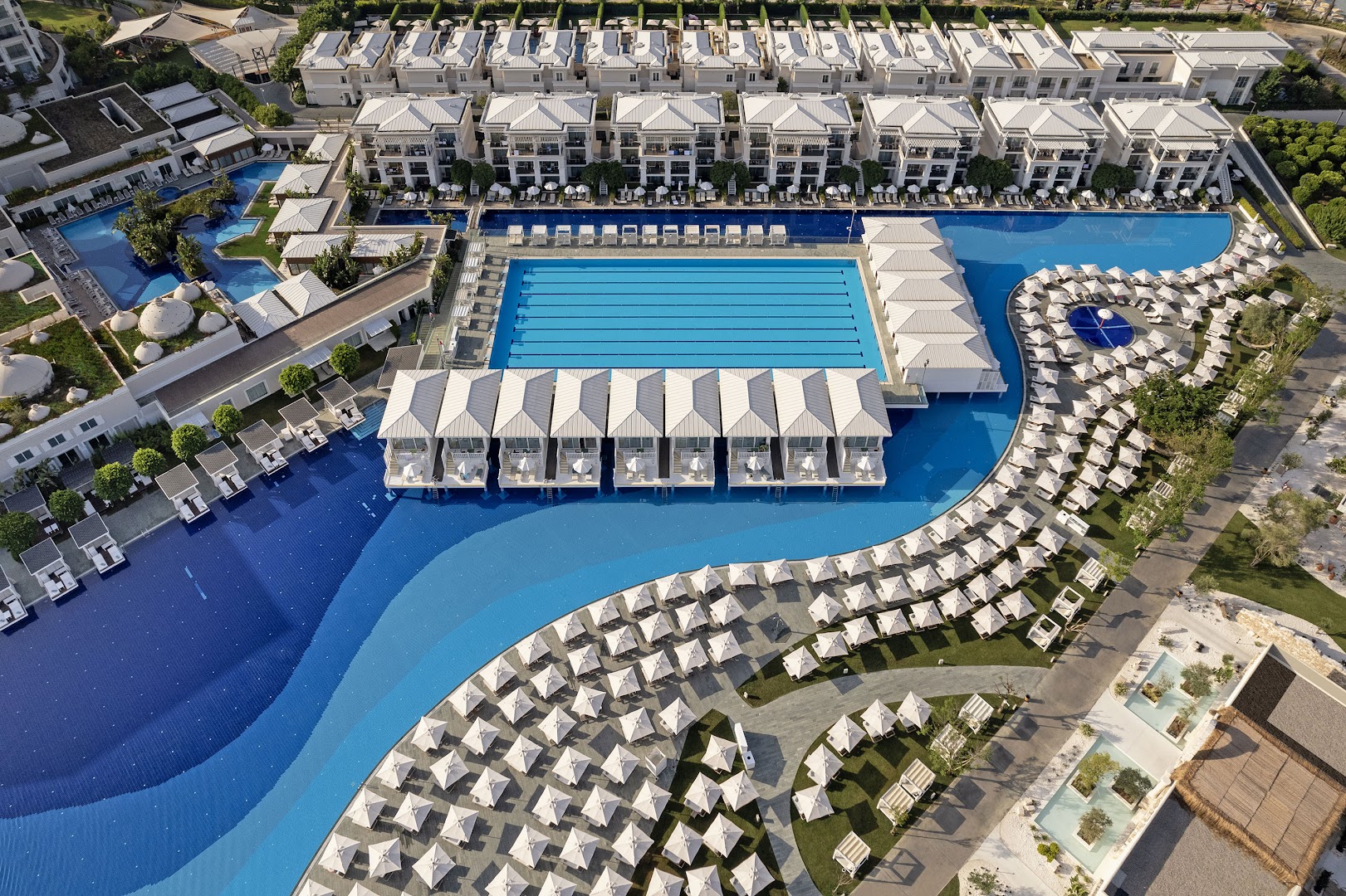 Titanic Deluxe Golf Belek viesnīcas plašais baseinu komplekss no putna lidojuma Belekā — redzami peldbaseini, sauļošanās zonas un bungalo tipa numuri