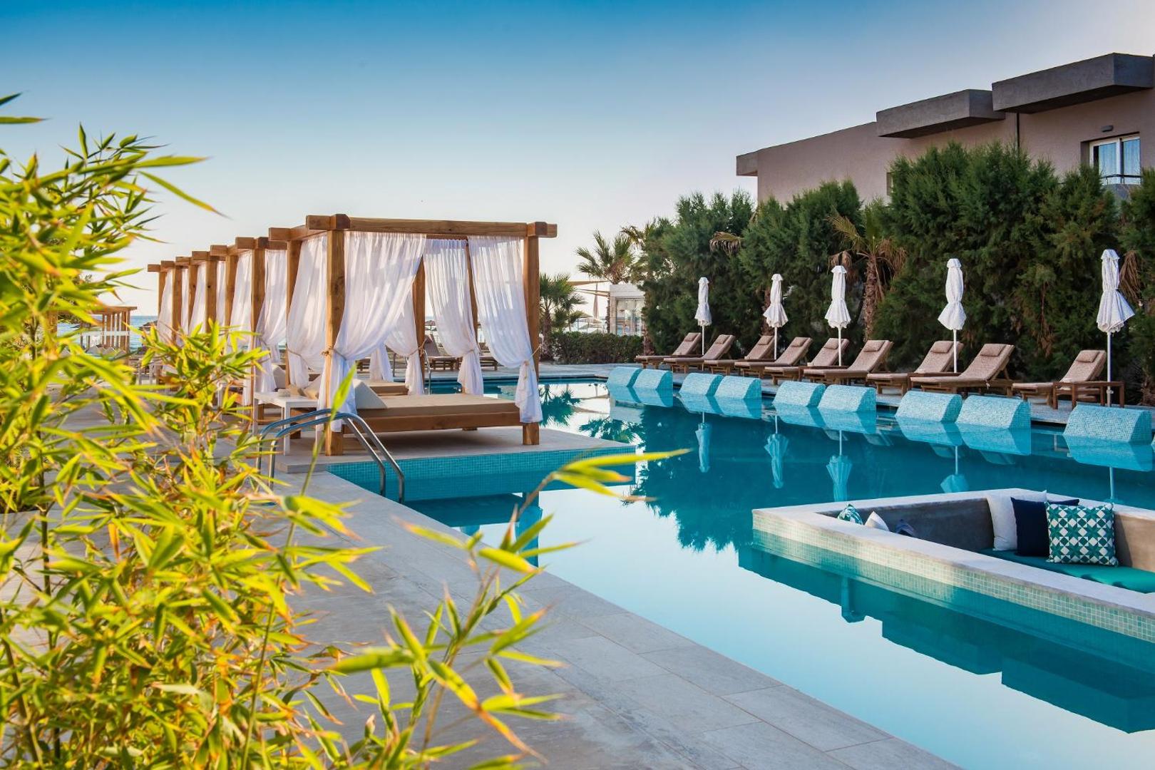 Paralos Lifestyle Beach baseina zona ar stilīgām atpūtas nojumēm un ūdenī iebūvētiem krēsliem saulainā dienā