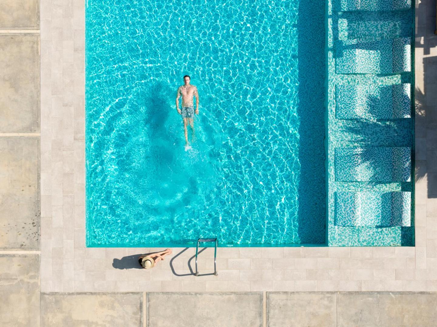Paralos Lifestyle Beach āra baseins no putna lidojuma skata Krētā — dzidri zils ūdens un sauļošanās zona ar krēsliem