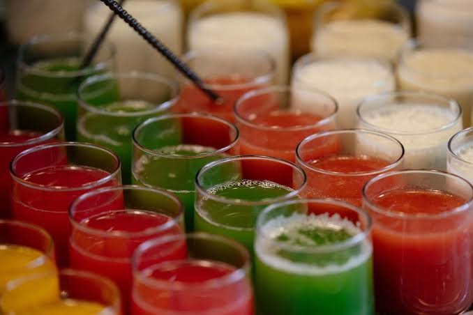 Tuvplāns ar daudzkrāsainām svaigi spiestām sulām un smūtijiem glāzēs Paralos Lifestyle Beach viesnīcas restorānā Krētā