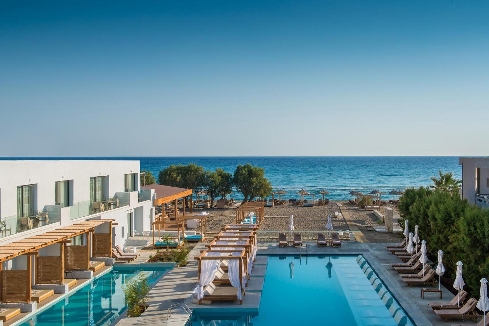 Paralos Lifestyle Beach viesnīcas kopskats Krētā ar āra baseinu, atpūtas krēsliem un tiešu piekļuvi smilšu pludmalei pie Vidusjūras