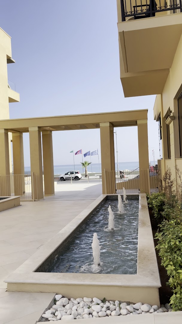 Atlantis Beach Hotel & Spa dekoratīvais ūdens baseins ar strūklakām pie ieejas un skatu uz jūru un karogiem