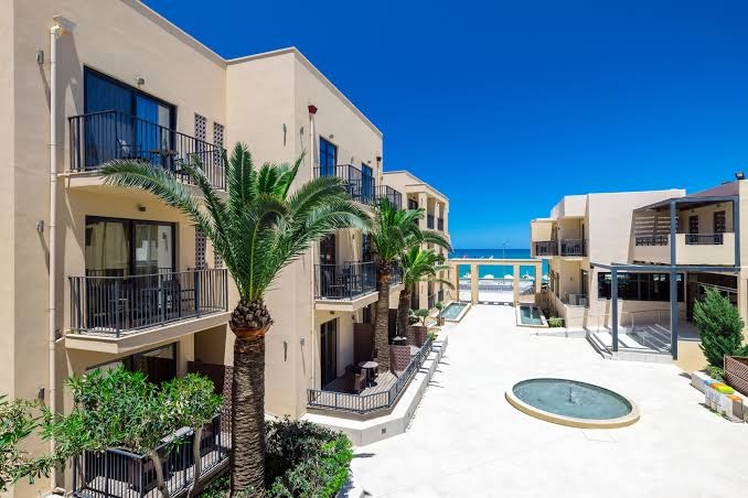 Skats no augšas uz Atlantis Beach Hotel & Spa korpusiem, balkoniem un palmu dārzu ar skatu uz jūras piekrasti