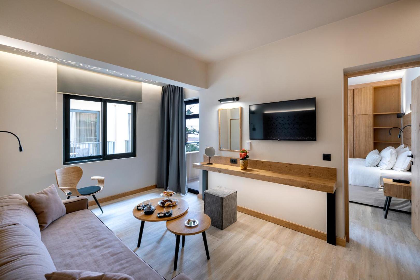 Atlantis Beach Hotel & Spa viesistabas zona ar dīvānu, galdiņiem, TV un skatu uz blakus esošo guļamistabu