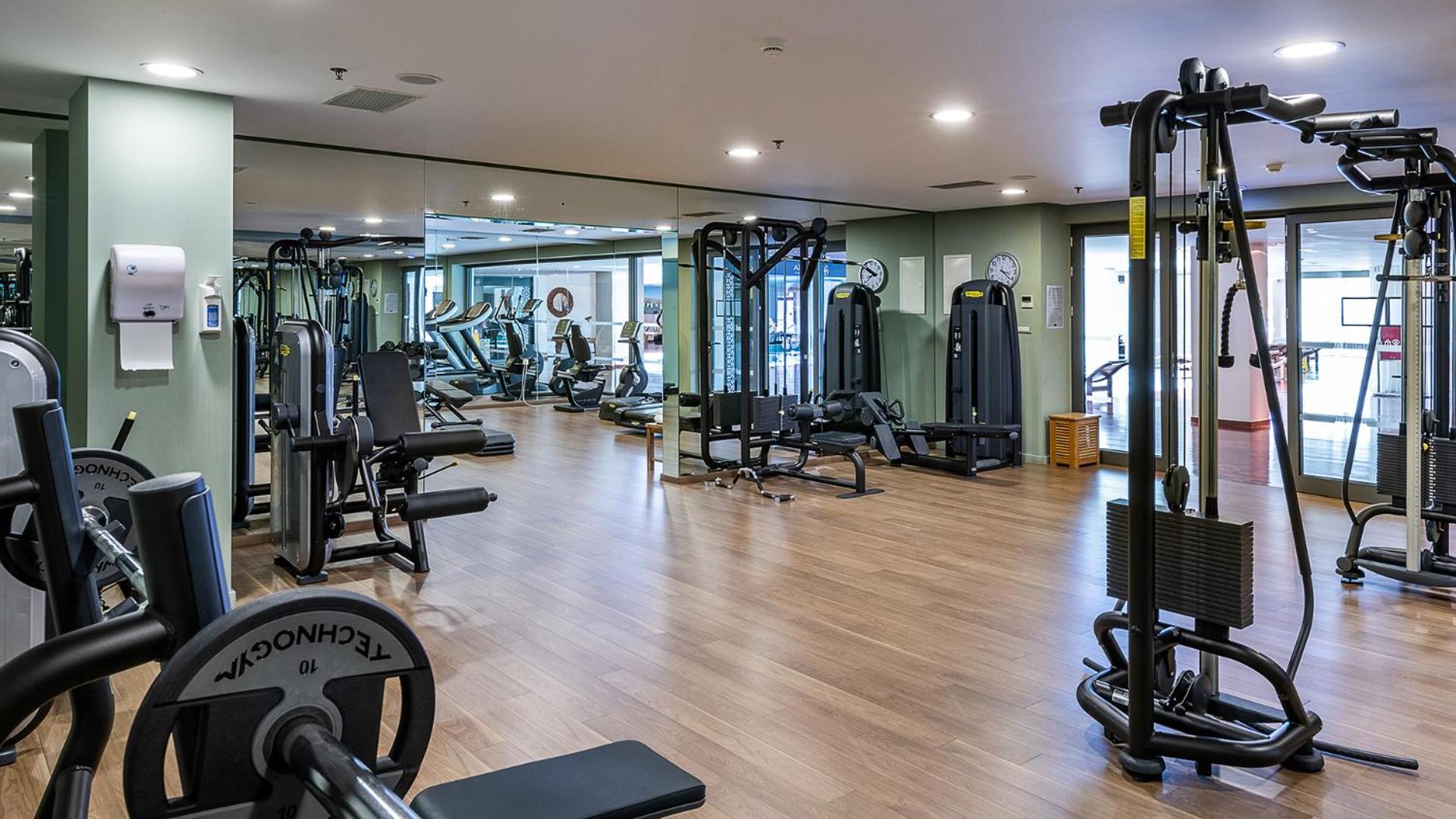 Avra Imperial Resort moderns fitness centrs ar Technogym aprīkojumu, spoguļsienu un koka grīdu sportiskām aktivitātēm