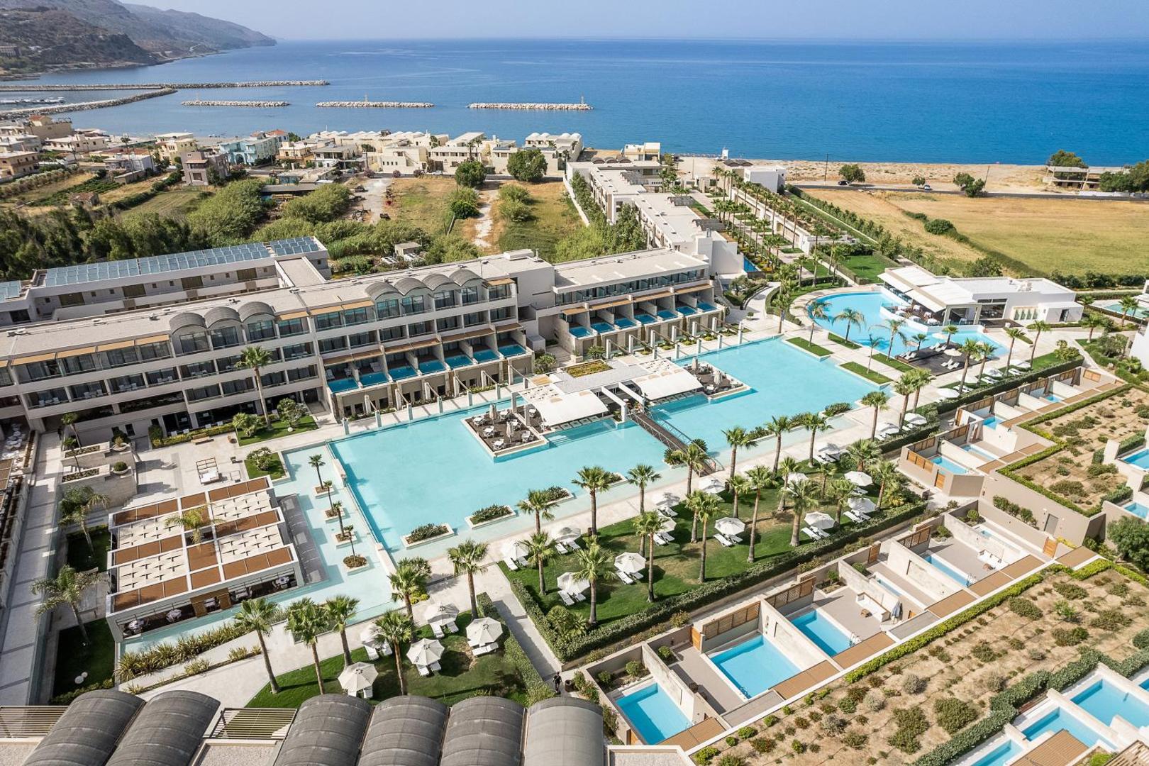 Avra Imperial Beach Resort panorāmas skats no putna lidojuma uz plašo baseinu kompleksu, viesnīcas korpusiem un jūras krastu Kolimbari, Krētā