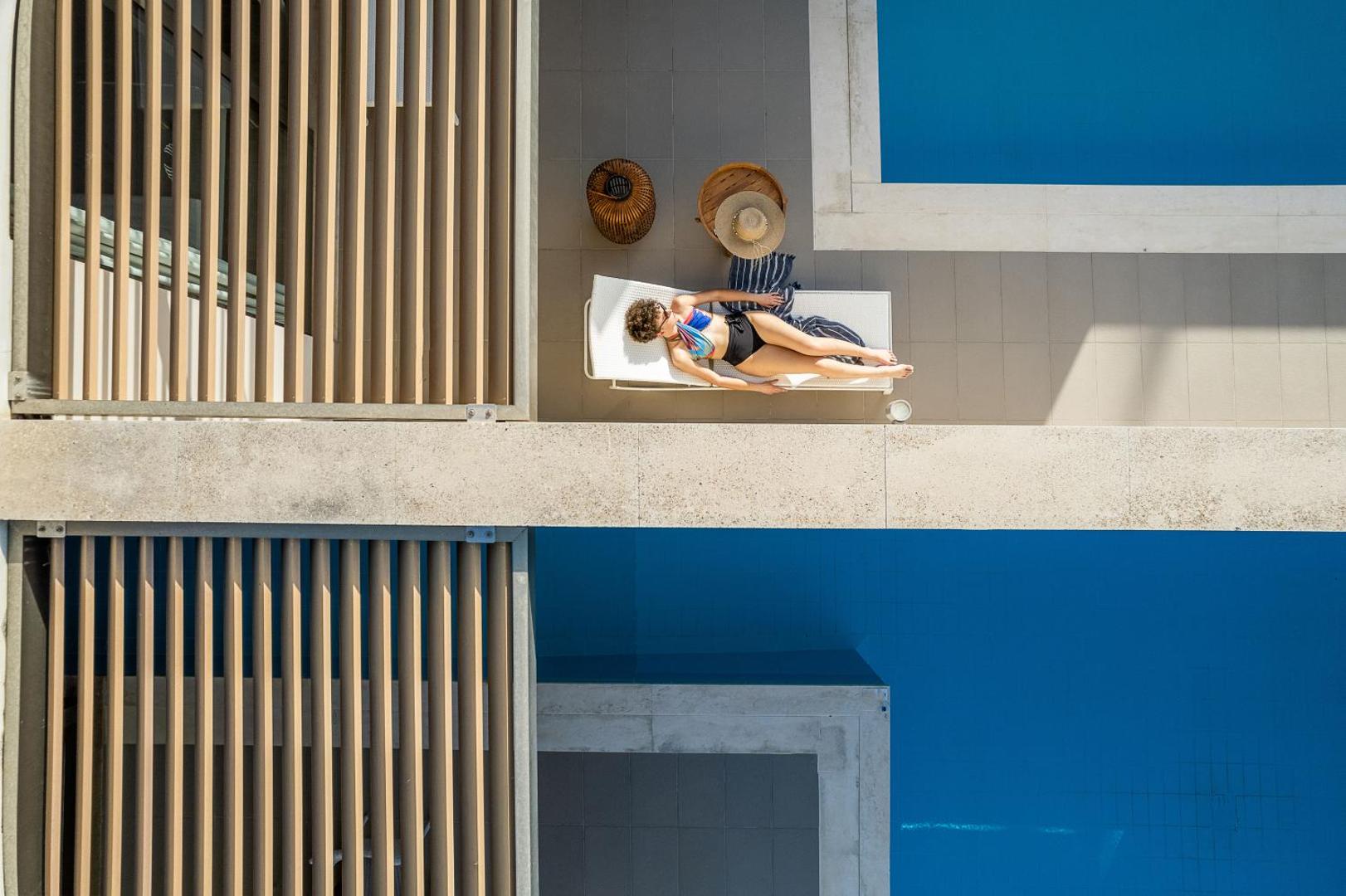 Avra Imperial Resort skats no augšas uz privāto baseinu un sauļošanās zonu — atpūtas krēsls un moderna arhitektūra Krētā