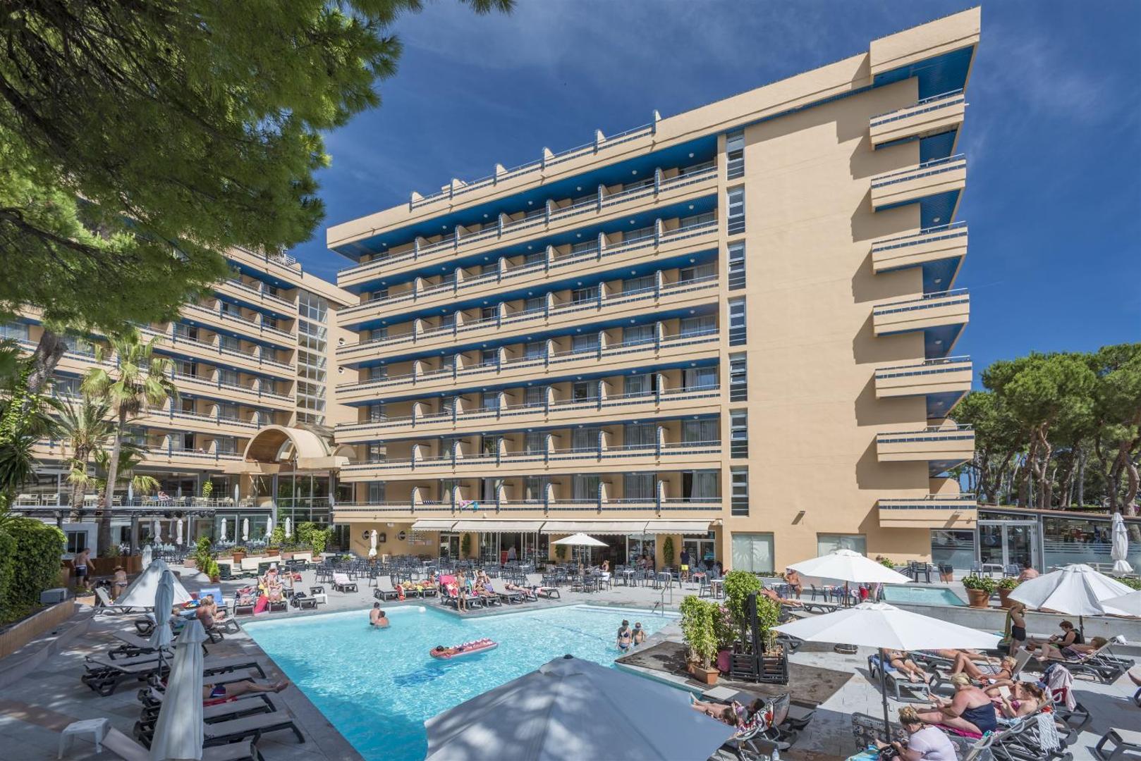4R Playa Park viesnīcas ēka un baseina teritorija ar atpūtniekiem un priežu ieskautu apkārtni Salovā.