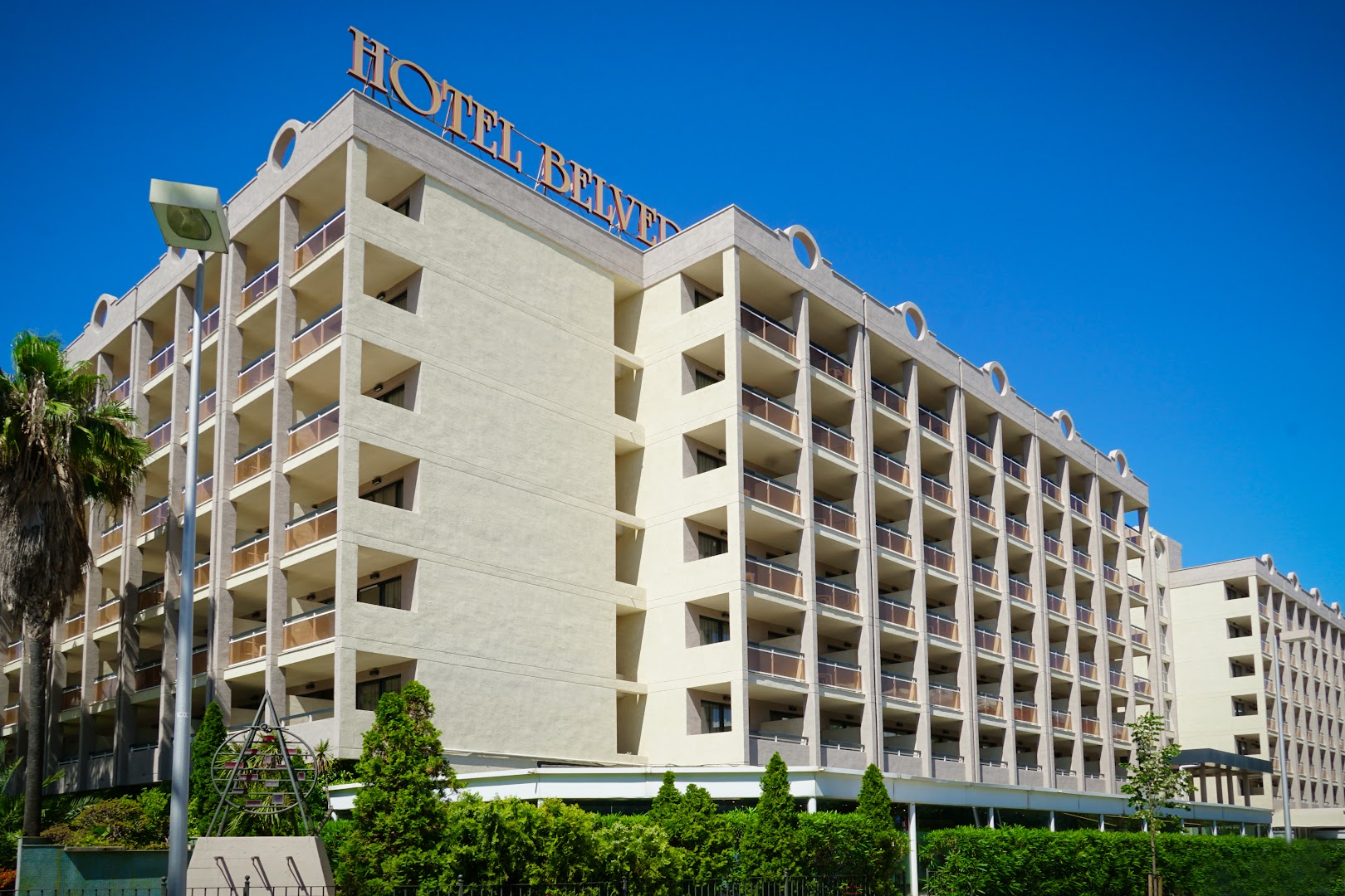 Ohtels Belvedere daudzstāvu ēkas fasāde ar balkoniem uz zilu debesu fona Salovā, Kostadoradas reģionā