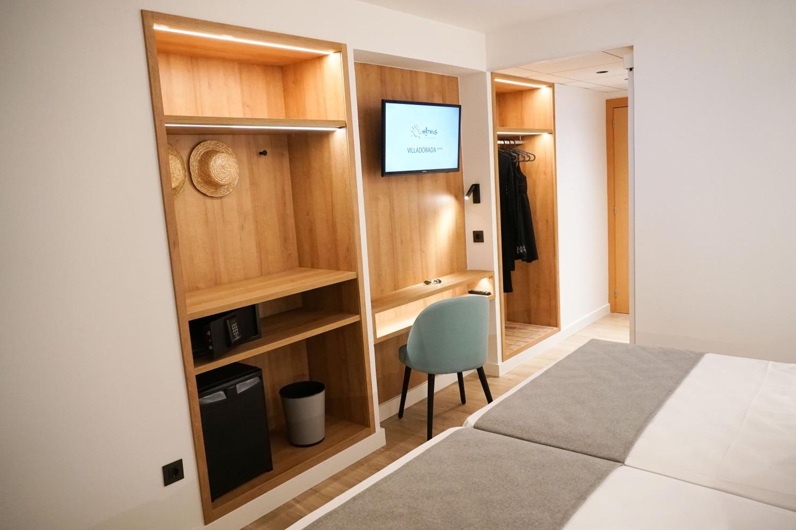 Ohtels Belvedere numura interjera detaļas — koka plaukti, minibārs, seifs un TV zona funkcionālam ceļojumam Salovā