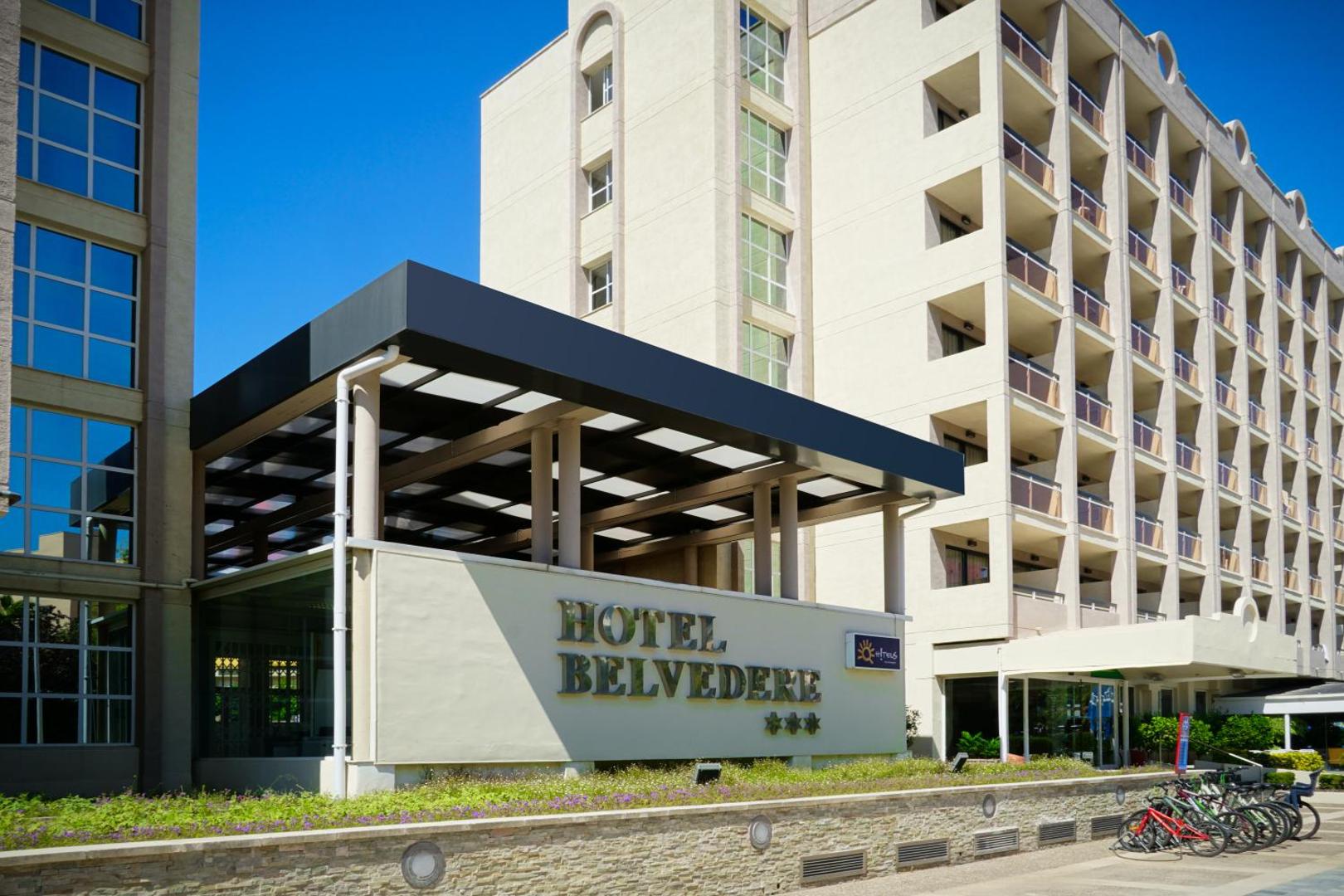 Ohtels Belvedere 3* viesnīcas ieeja un fasāde Salovā — redzams zīmols, velosipēdu novietne un modernā arhitektūra