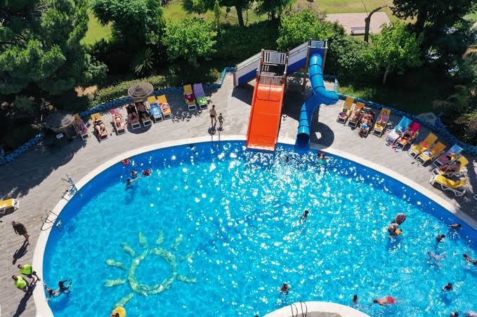 Ohtels Belvedere bērnu baseins ar krāsainiem slidkalniņiem un saules simbolu baseina dibenā Salovā, Spānijā