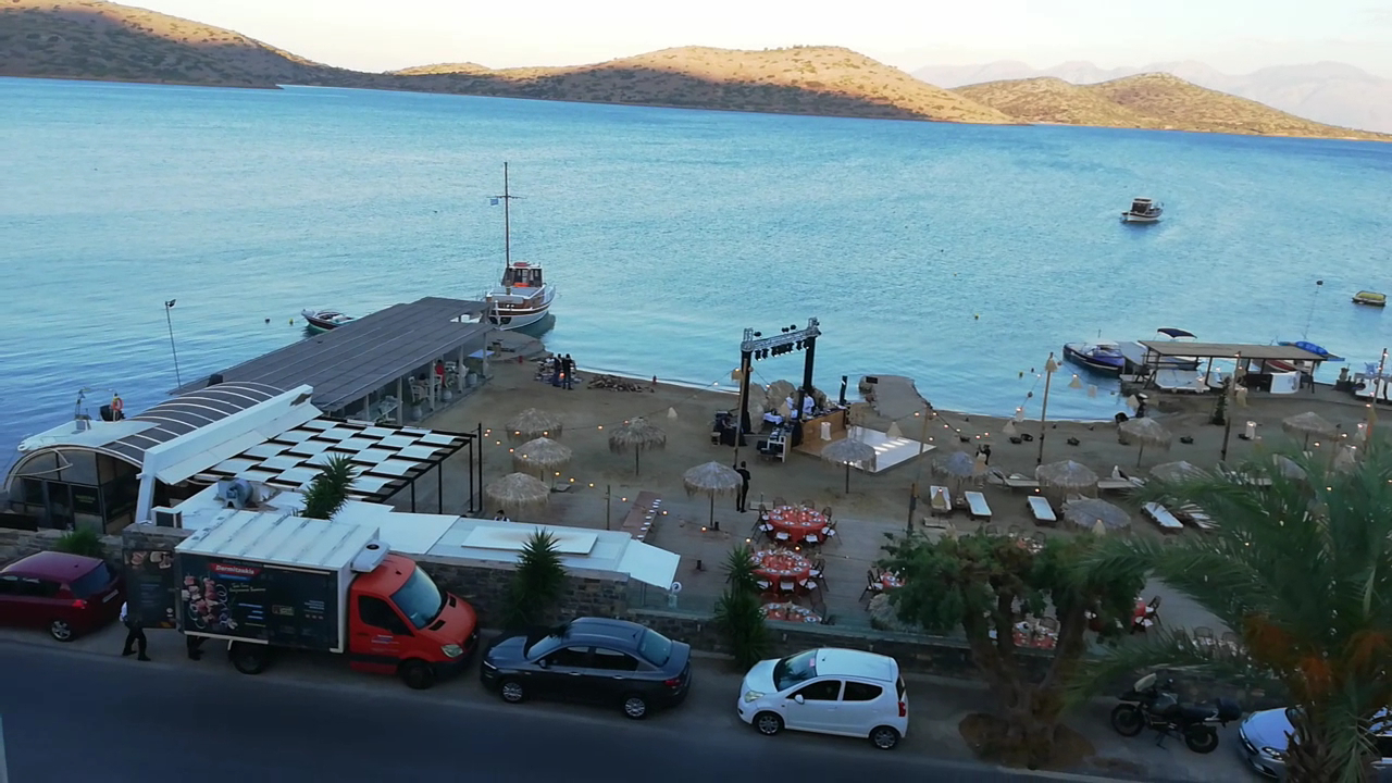 Royal Marmin Bay Boutique & Art Hotel pludmales pasākumu norises vieta vakarā ar svētku galdiem, skatuvi un kalnu ainavu fonā.