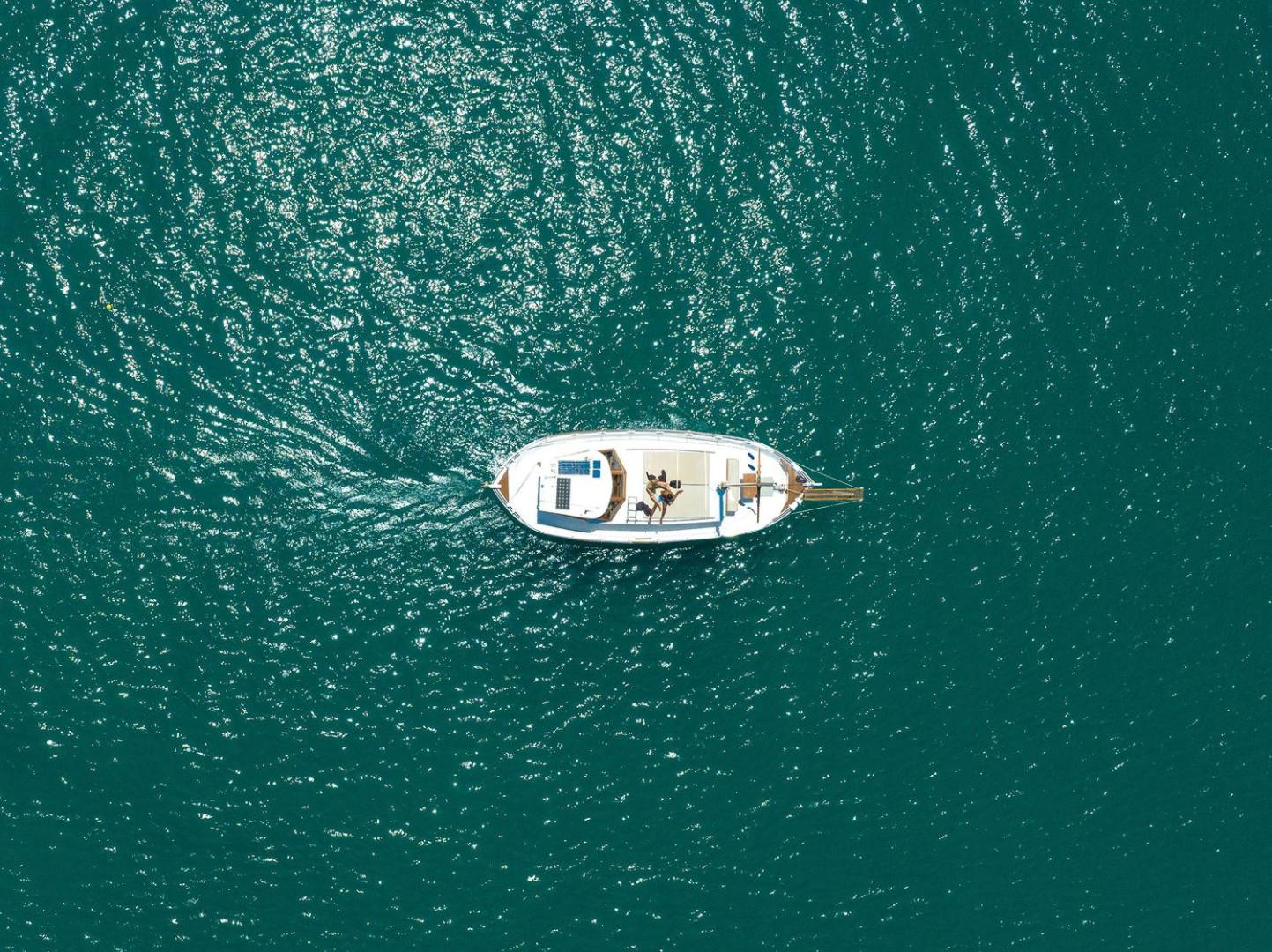 Skats no augšas uz baltu motorjahtu dzidri zilajos Krētas piekrastes ūdeņos netālu no Royal Marmin Bay viesnīcas
