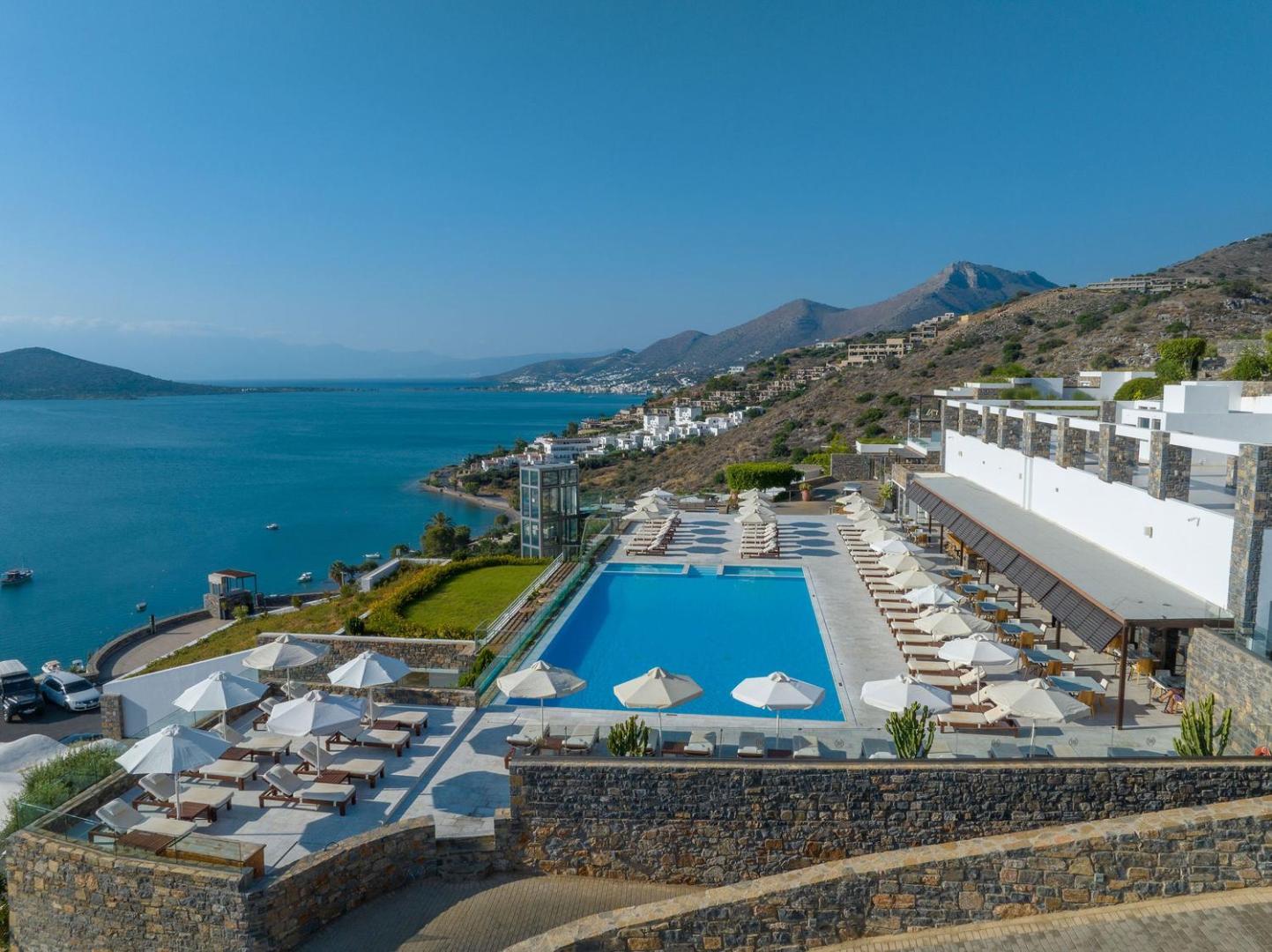 Royal Marmin Bay Boutique & Art Hotel arhitektūra un baseina zona no augšas, parādot viesnīcas atrašanās vietu piekrastes nogāzē.