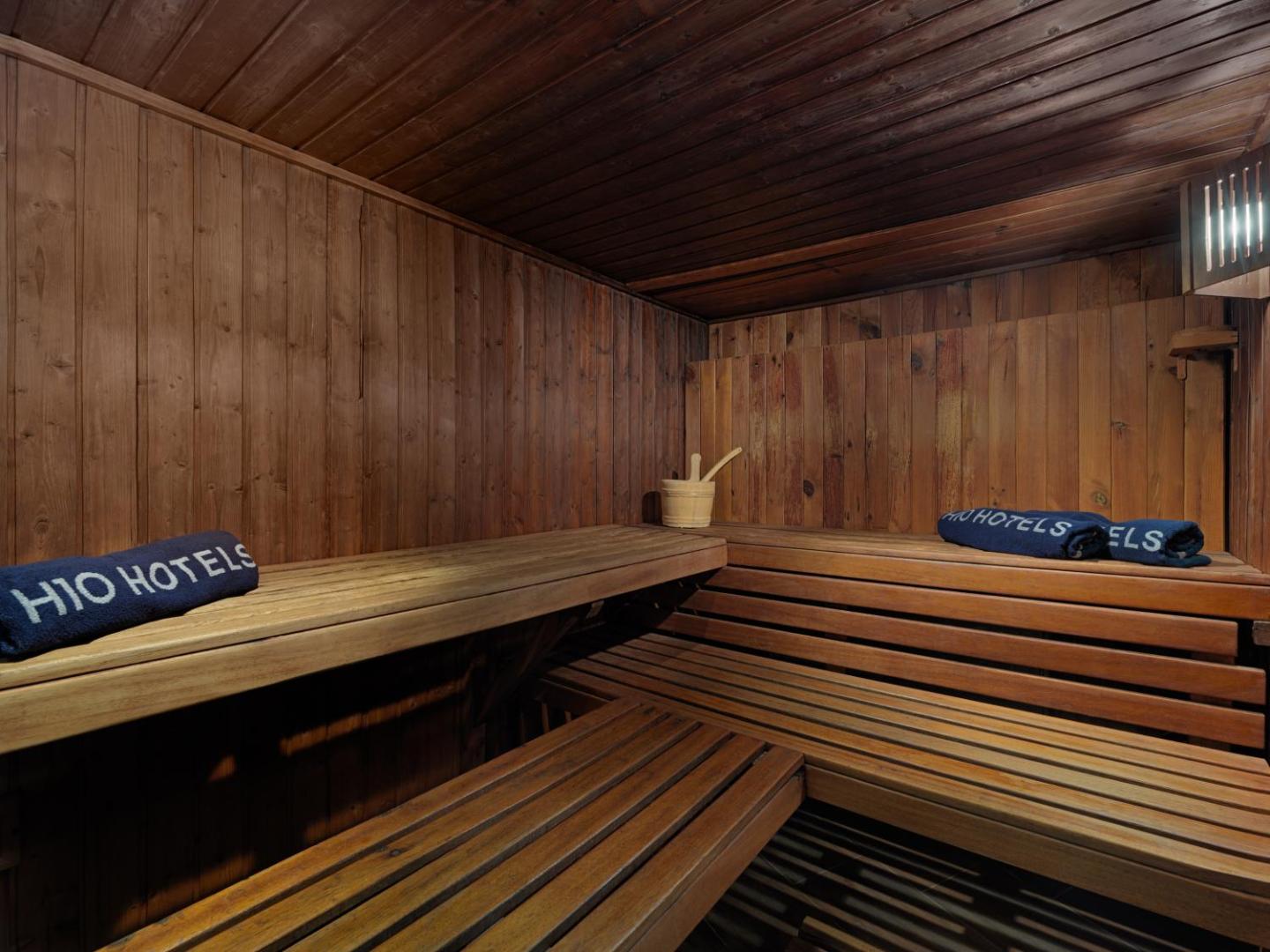 H10 Salou Princess viesnīcas koka apdares sauna ar daudzpakāpju soliem un ziliem dvieļiem relaksācijai spa zonā Salovā, Spānijā.