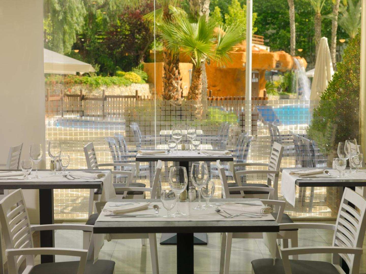 H10 Salou Princess restorāna terase ar skatu uz baseinu un palmām — balti klāti galdi un gaišs interjers