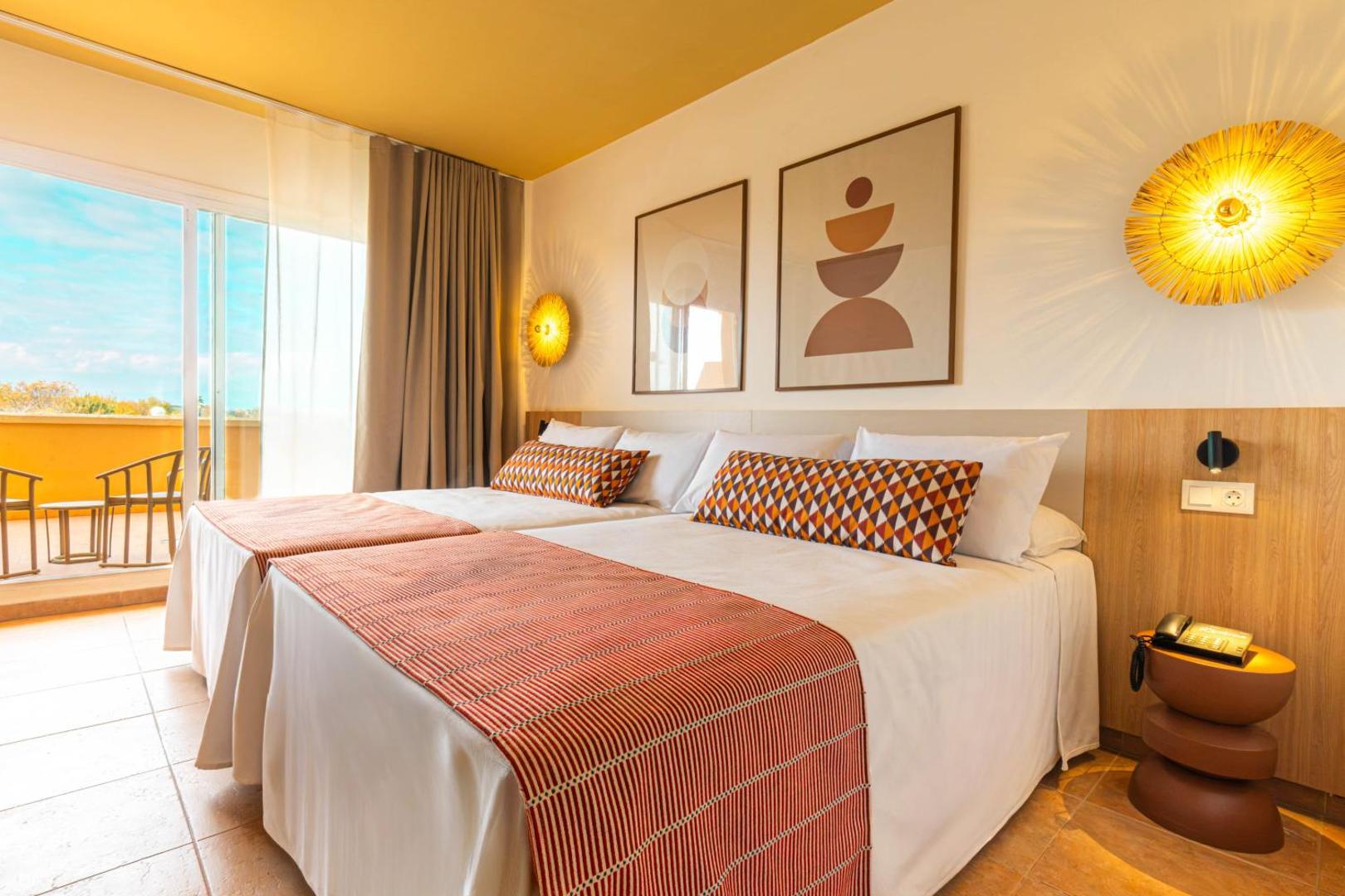 Ohtels La Hacienda gaišs viesnīcas numurs ar divām gultām, modernu interjeru un balkonu, no kura paveras skats uz kūrortu.