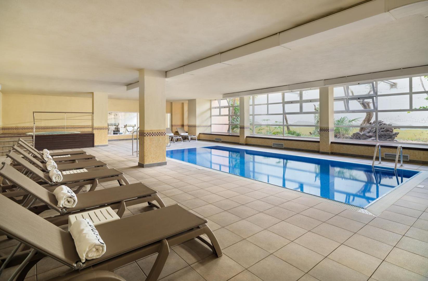 H10 Salauris Palace iekštelpu baseins ar apsildi, lieliem logiem un ērtiem zviļņiem relaksācijai spa zonā Kosta Doradas reģionā