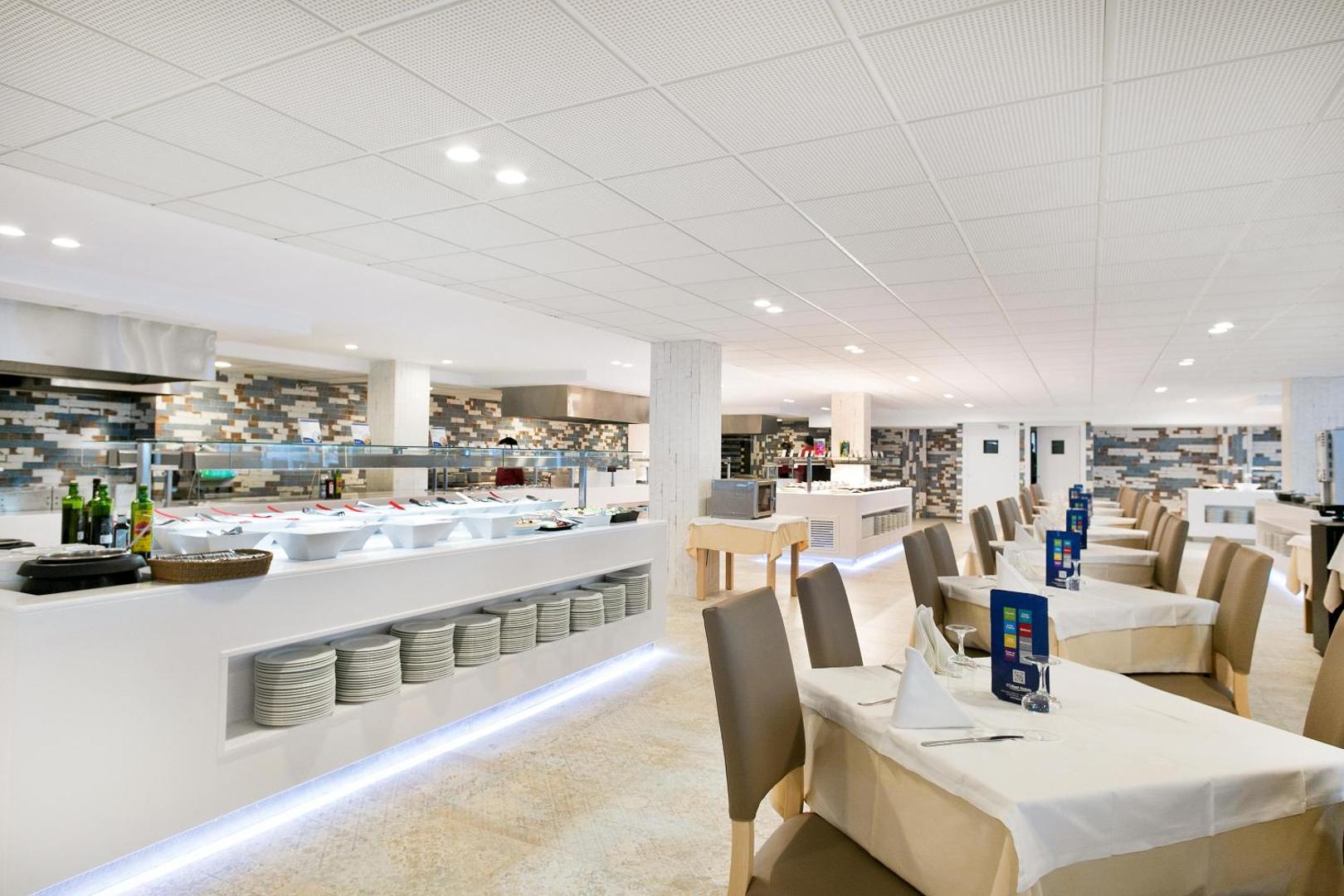 Best Maritim viesnīcas galvenais restorāns ar bufetes tipa galdiem un servētiem galdiņiem gaišā, modernā interjerā Kambrilsā, Spānijā