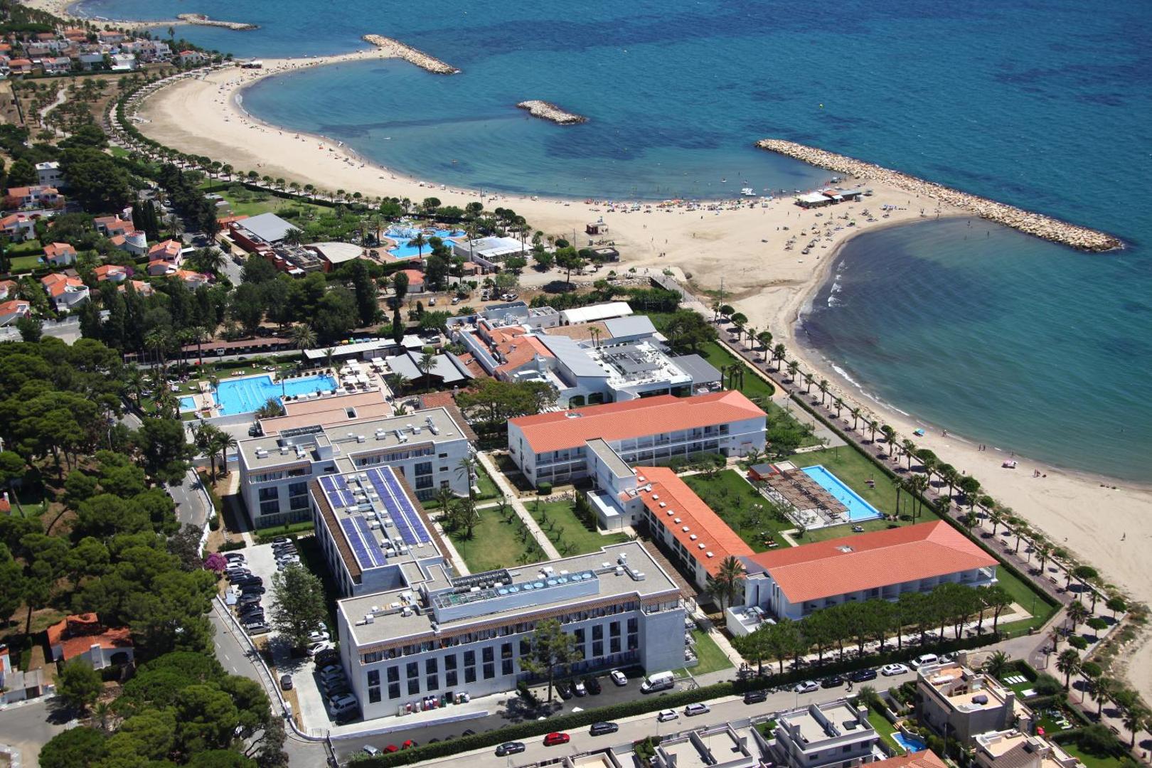 Estival Eldorado Resort aerofotoattēls Kambrilsā, Spānijā — skats uz viesnīcas kompleksu, āra baseiniem un plašo smilšu pludmali Vidusjūras krastā