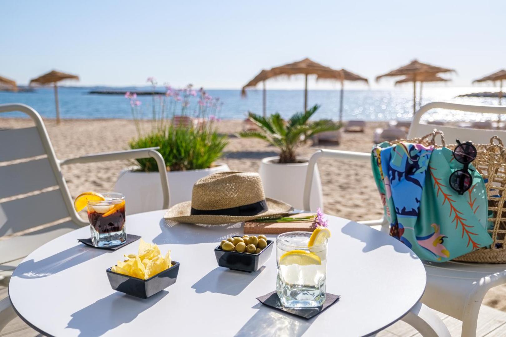 Estival Eldorado Resort galdiņš ar uzkodām un dzērieniem, skats uz Vidusjūru un pludmales saulessargiem Kosta Doradas reģionā.