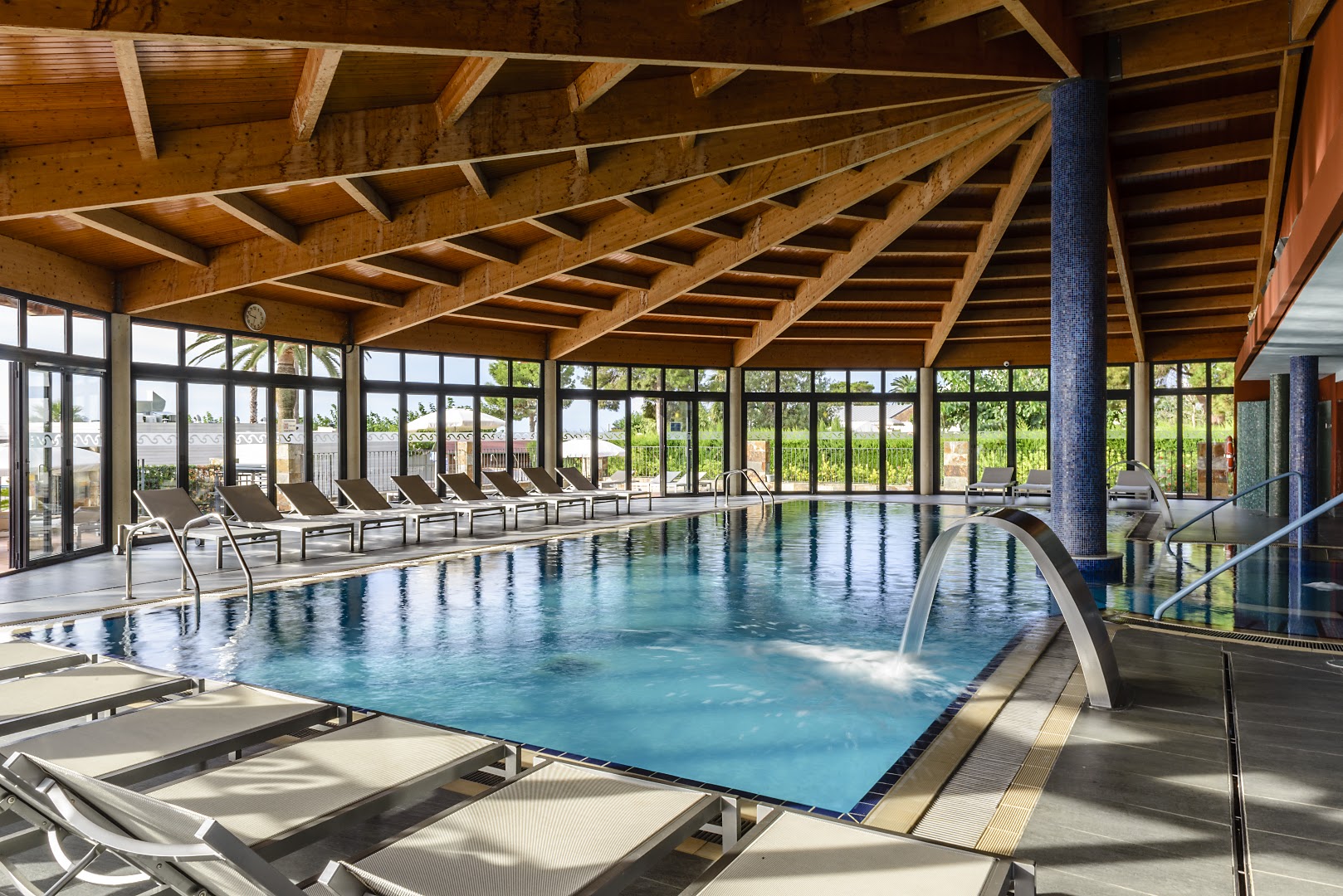 Estival Eldorado Resort iekštelpu baseins ar koka griestu apdari un masāžas strūklu — atpūtas zona ar zviļņiem un lieliem logiem