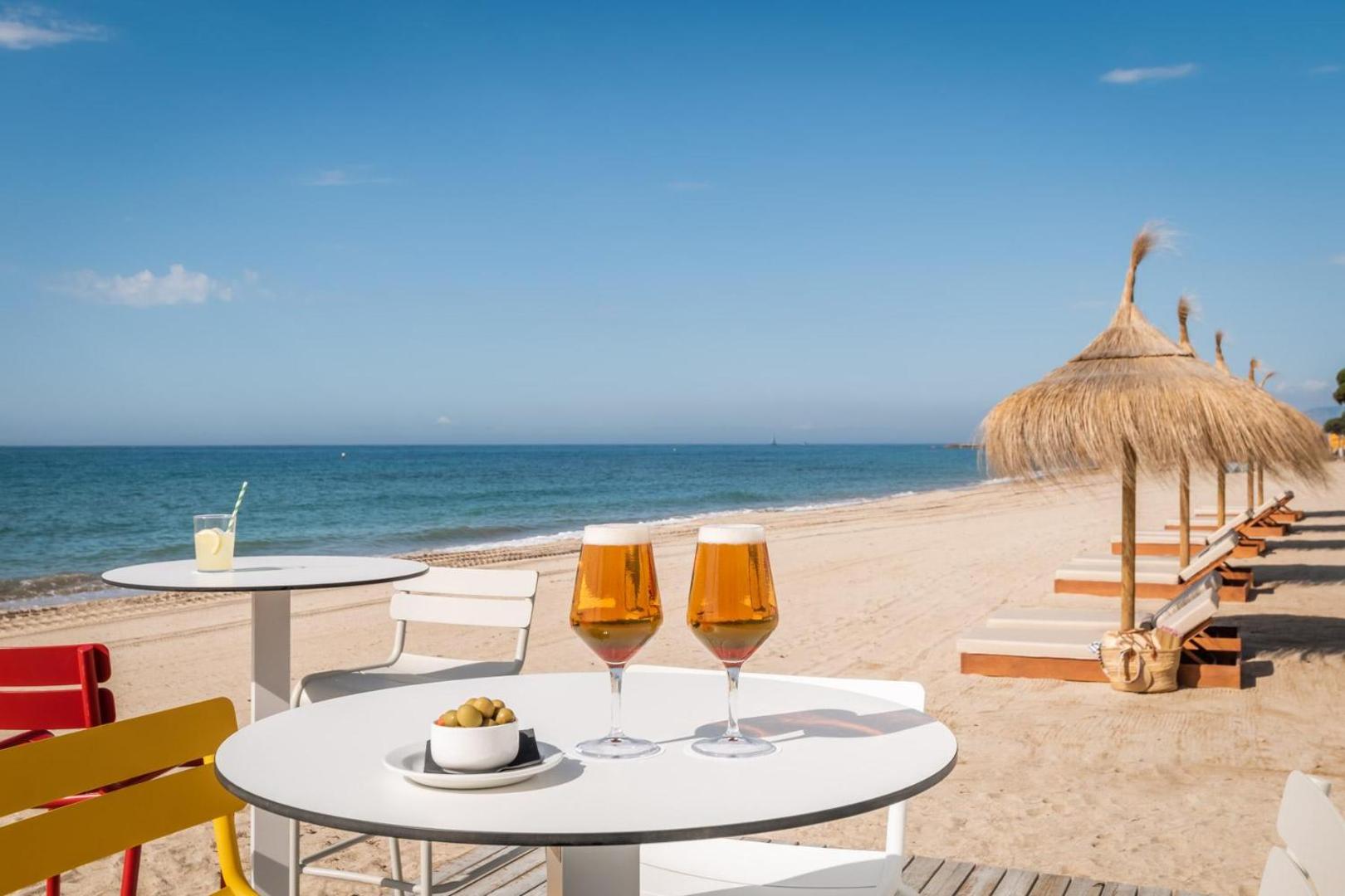 Atsvaidzinoši dzērieni un olīvas uz galda Estival Centurion Playa pludmales terasē ar skatu uz jūru un saulessargiem