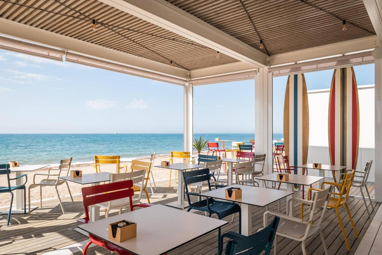 Estival Centurion Playa pludmales bārs ar krāsainiem krēsliem un sērfinga dēļu dekorācijām pie pašas jūras krasta līnijas