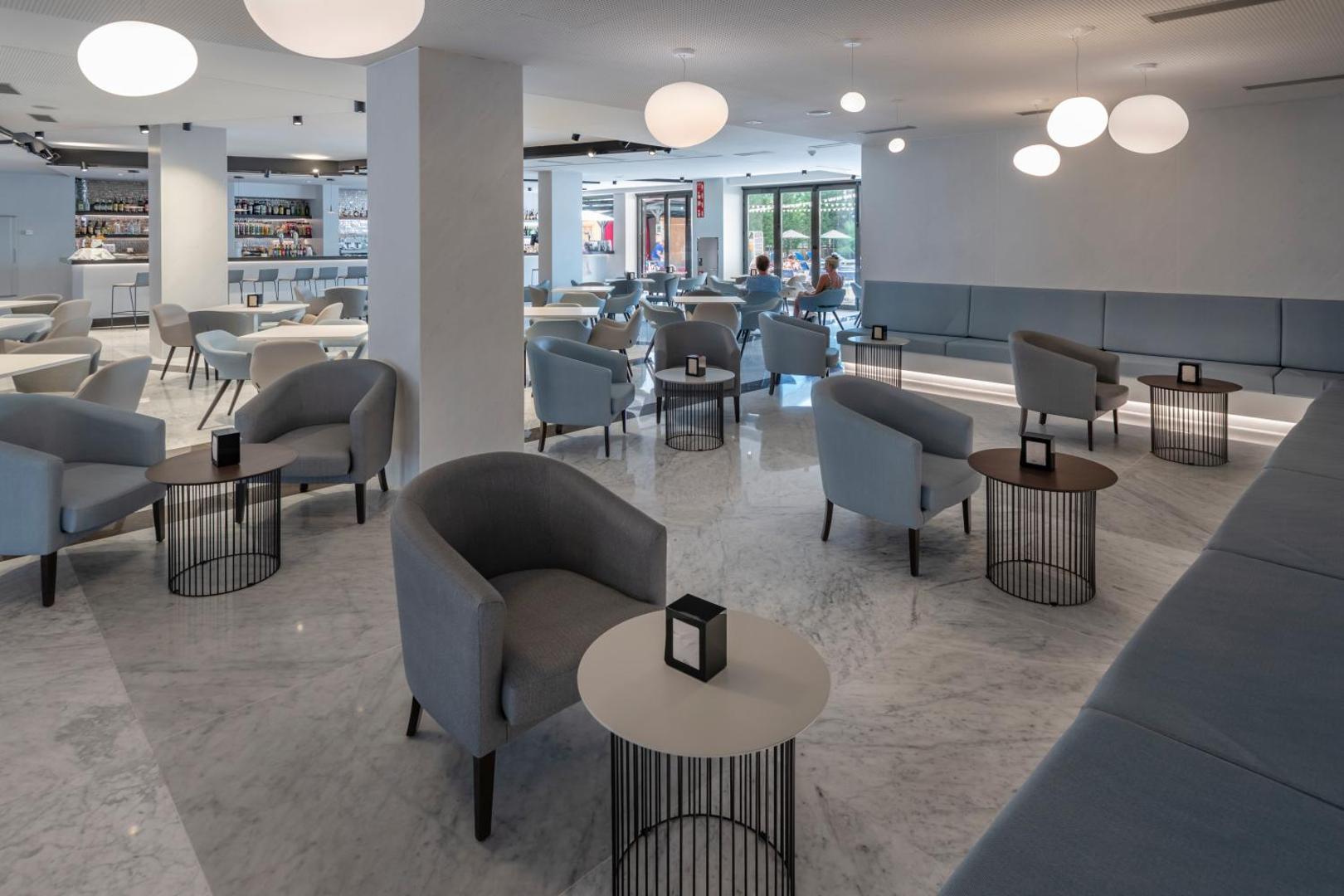 Olympus Palace viesnīcas lobby bārs un atpūtas telpa ar mīkstajiem krēsliem, marmora grīdu un bāra leti fonā