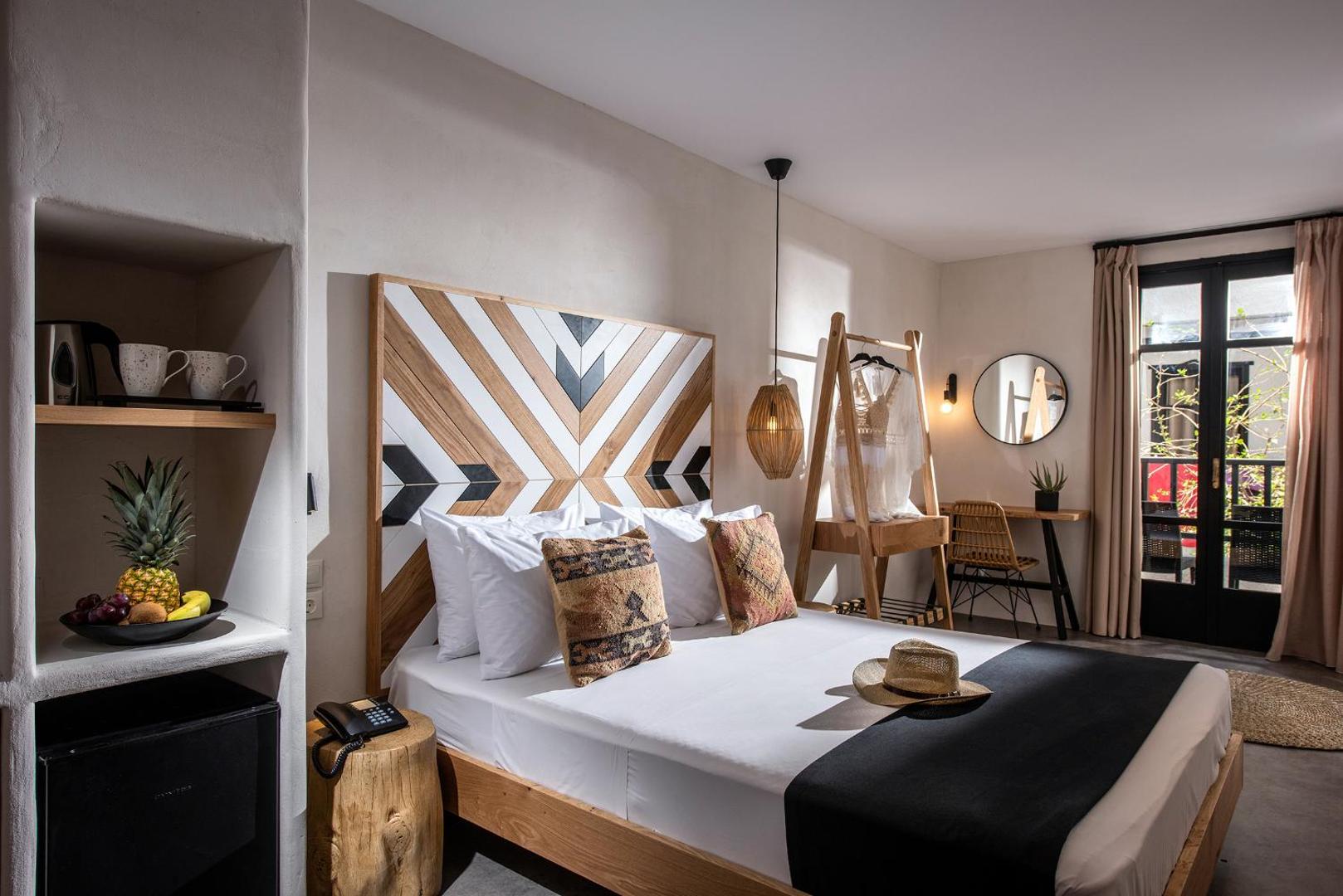 Indigo Inn Casa viesnīcas numurs ar koka dizaina elementiem, lielu gultu un dekoratīvu galvgali Hersonisā, Krētā