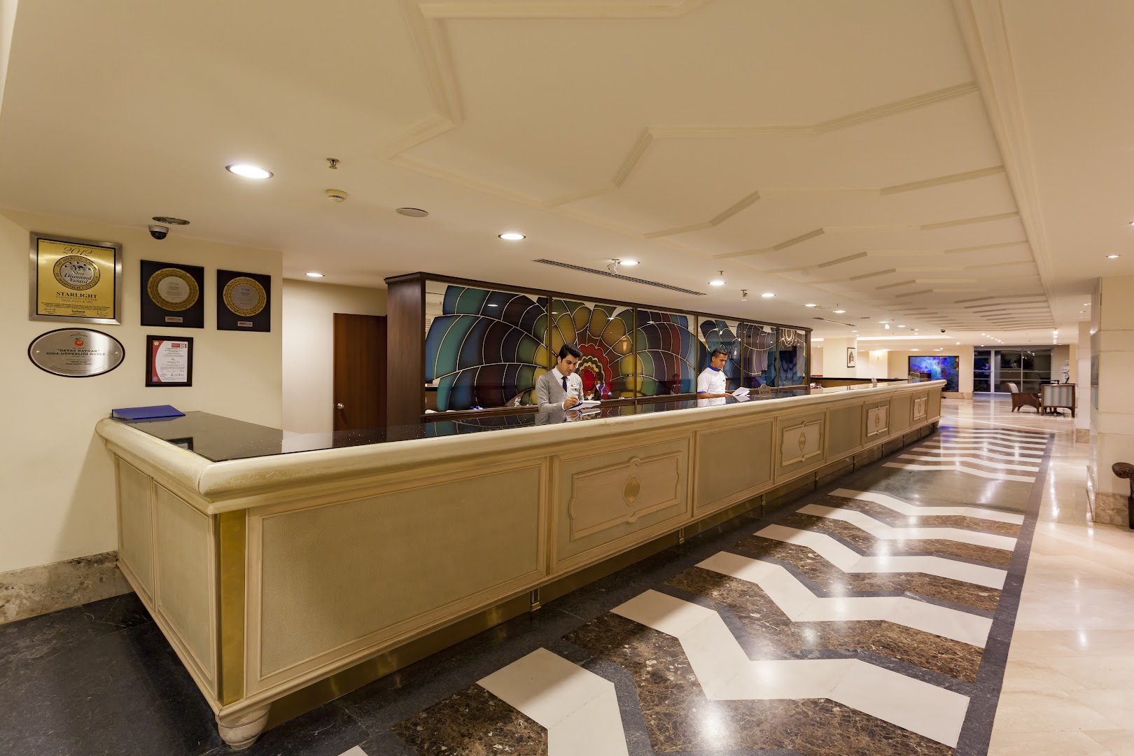 Starlight Resort viesnīcas lobby recepcijas zona ar garu apkalpošanas leti, marmora grīdu un dekoratīviem sienas elementiem